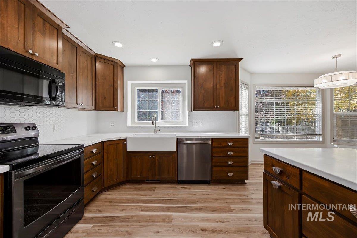 Kitchen featuring stainless steel appliances, light wood-style floors, decorative backsplash, dark brown cabinets, and recessed lighting