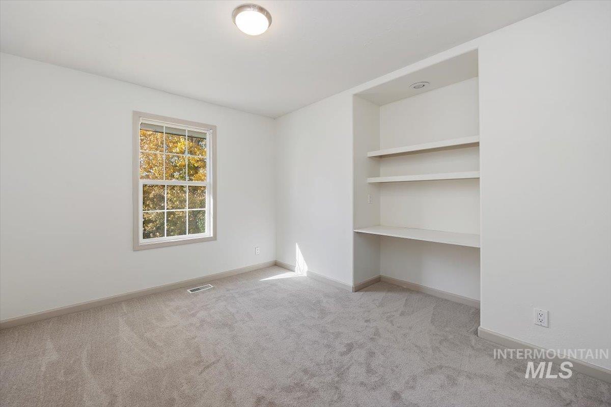 Spare room featuring light colored carpet and baseboards