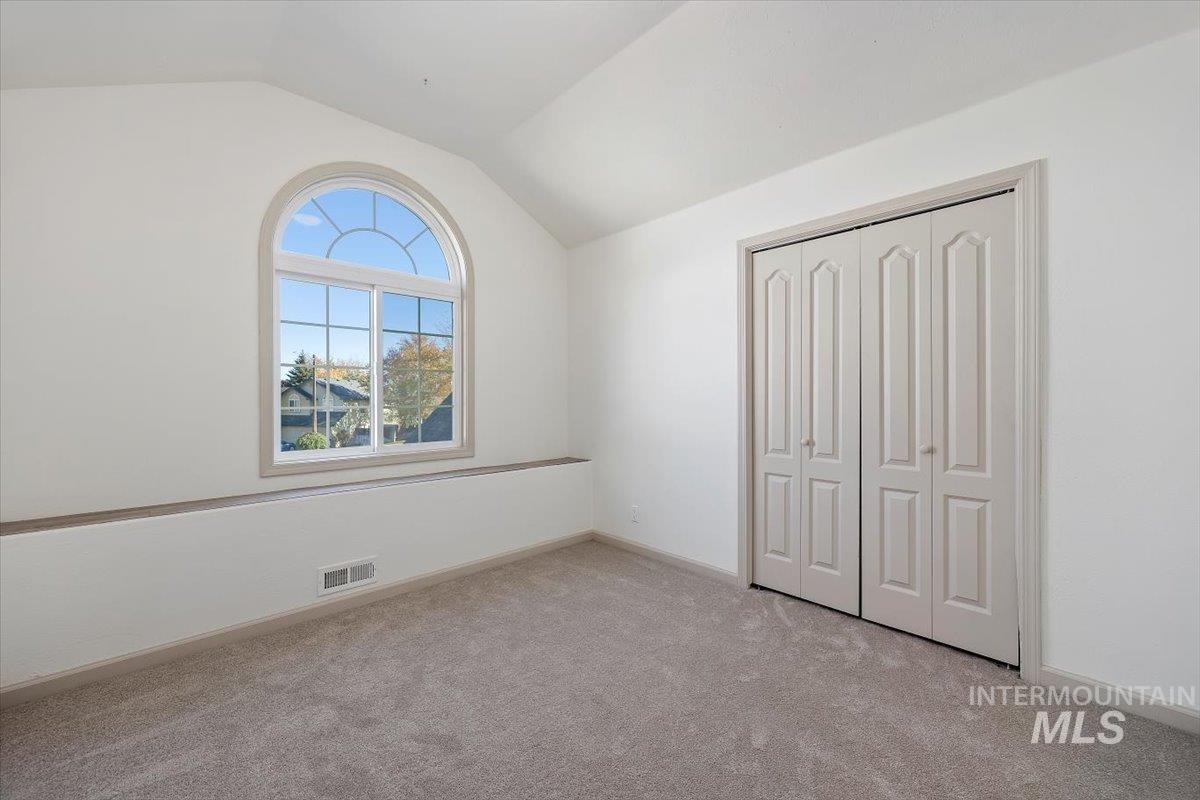 Unfurnished bedroom with vaulted ceiling, light colored carpet, and a closet