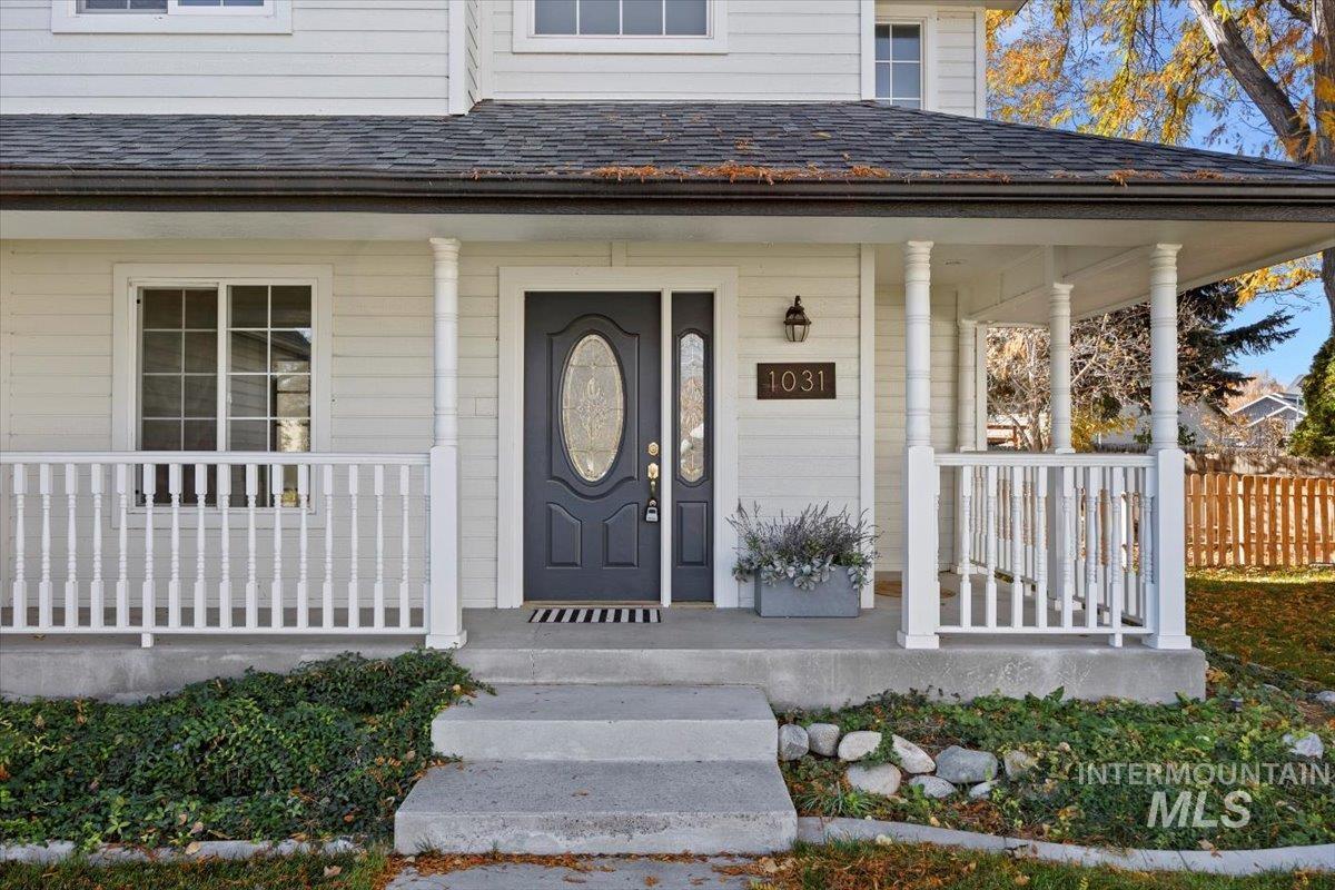 Doorway to property with a porch and roof with shingles