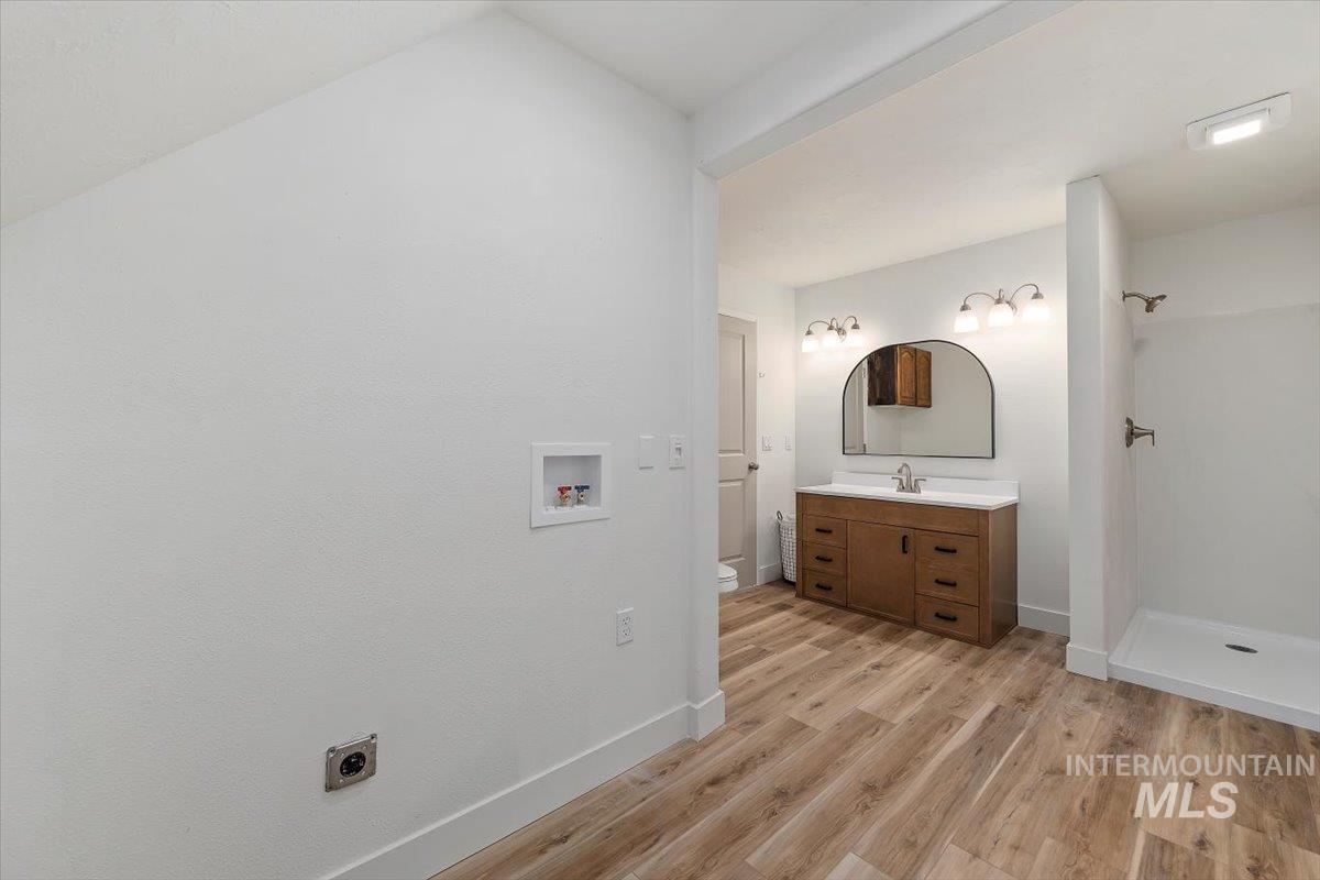 Full bath with light wood-style flooring, vanity, and a shower
