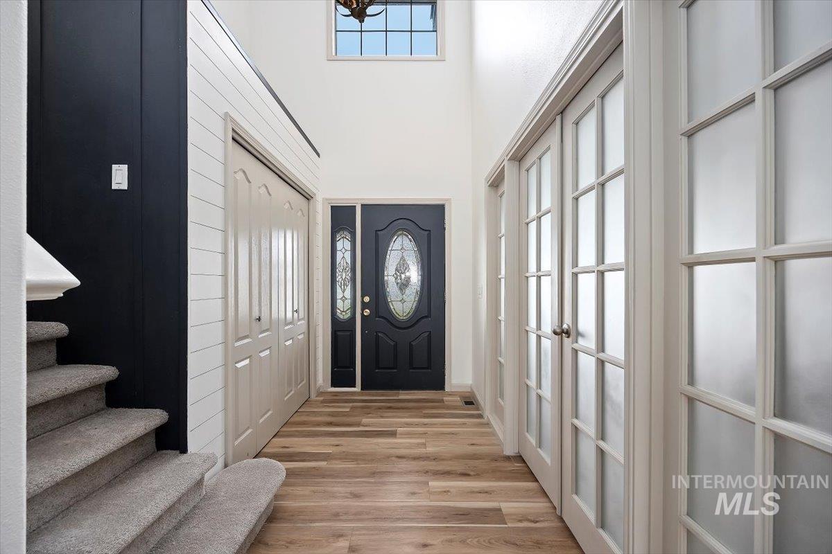 Entrance foyer featuring light wood-type flooring, a towering ceiling, and stairs