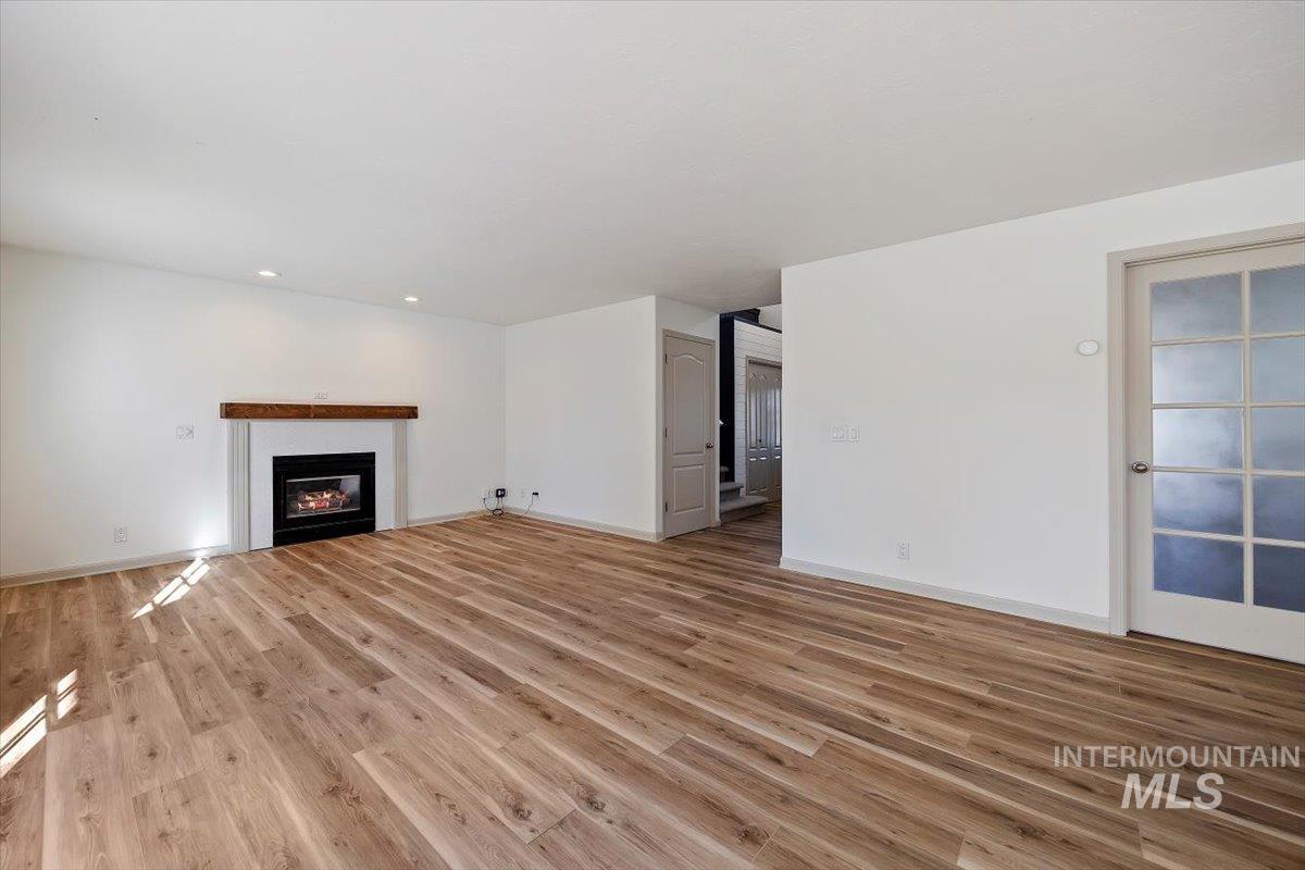 Unfurnished living room with light wood-type flooring and a glass covered fireplace