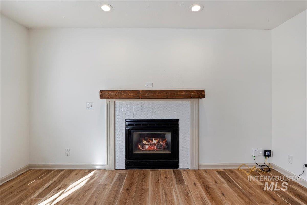 Detailed view of a glass covered fireplace, wood finished floors, and recessed lighting