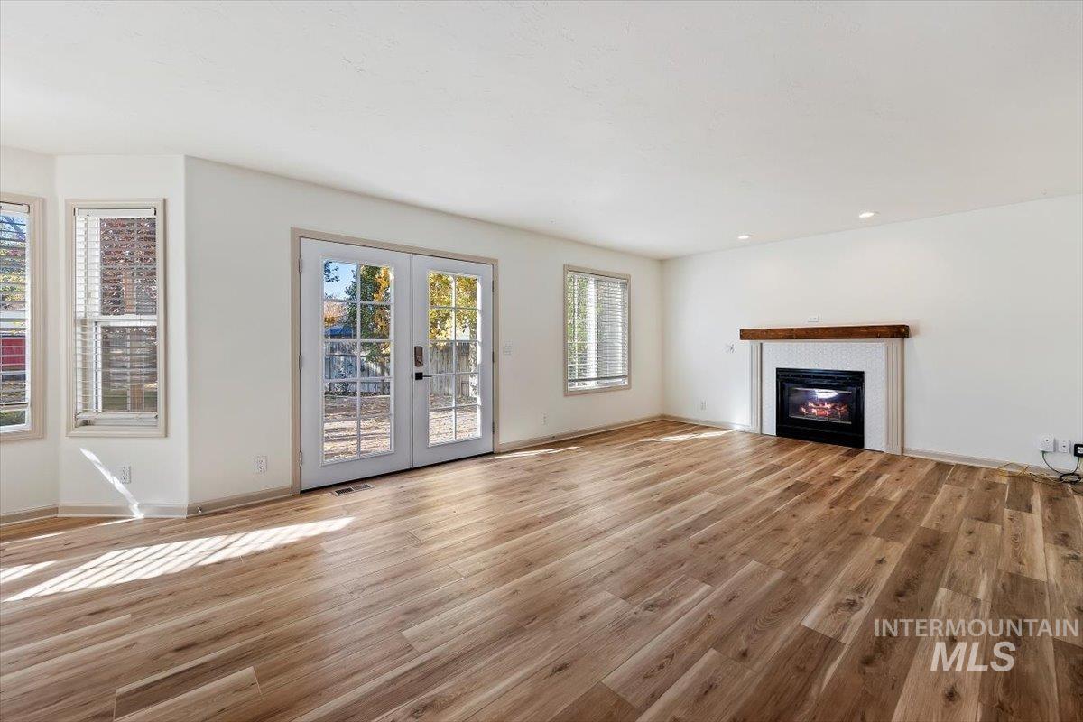 Unfurnished living room featuring french doors, light wood-style floors, a glass covered fireplace, and recessed lighting