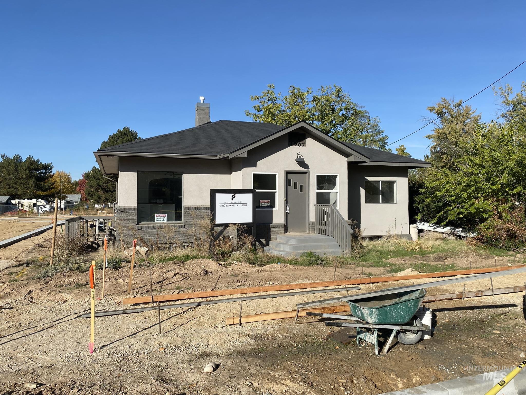 View of front facade featuring stucco siding, a chimney, brick siding, and roof with shingles