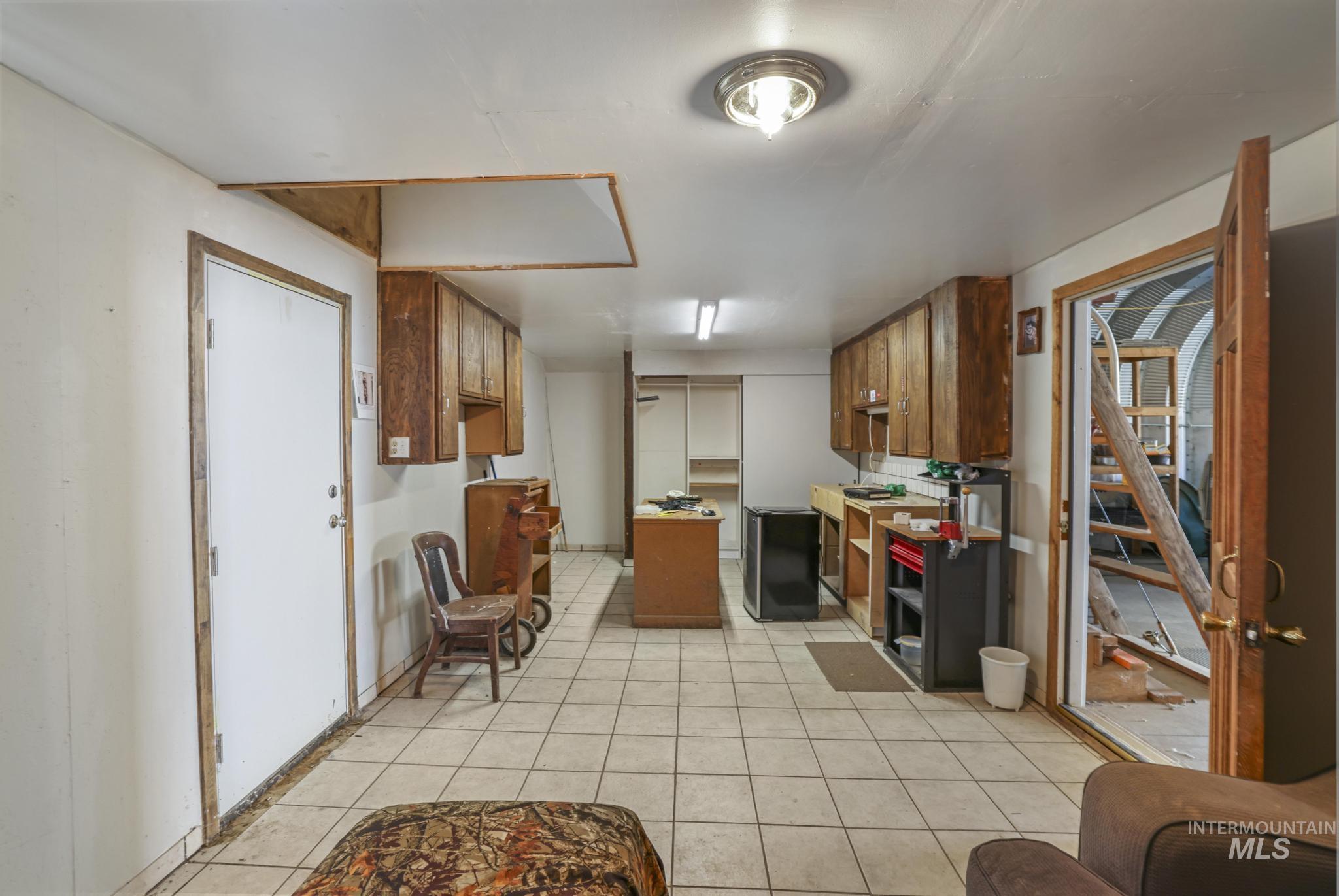 Kitchen featuring brown cabinets, light tile patterned floors, fridge, and light countertops
