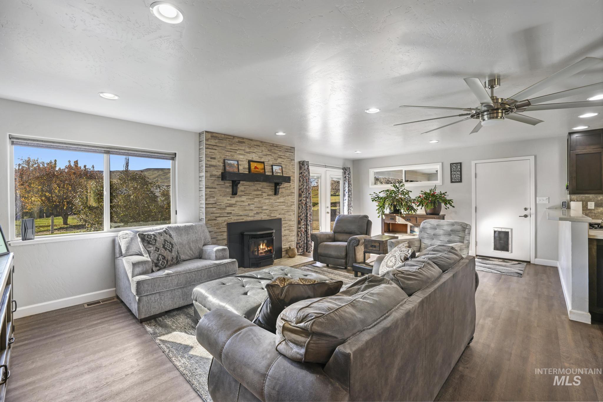 Living area with dark wood finished floors, recessed lighting, a stone fireplace, and a textured ceiling