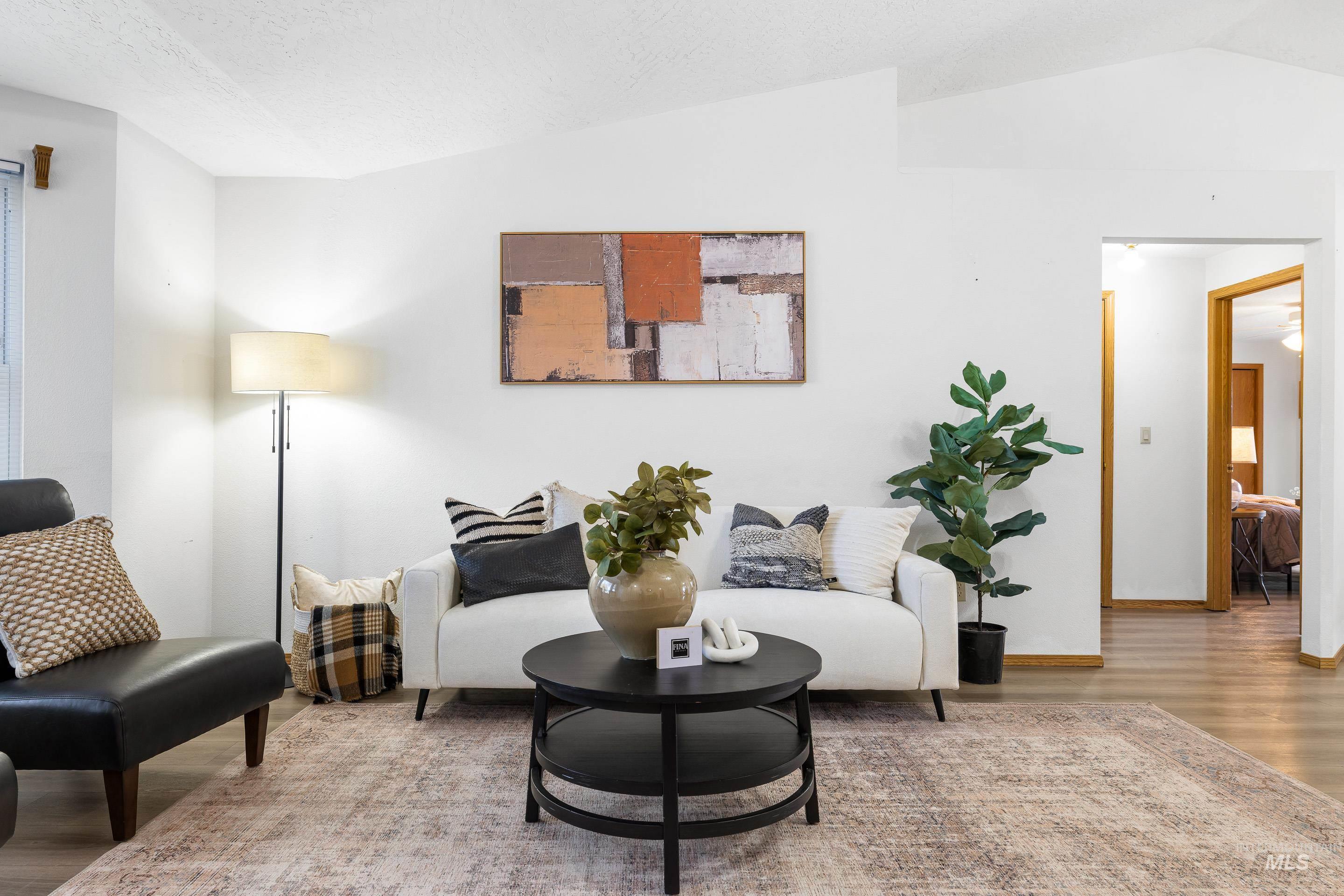 Living area featuring wood finished floors, vaulted ceiling, and a textured ceiling