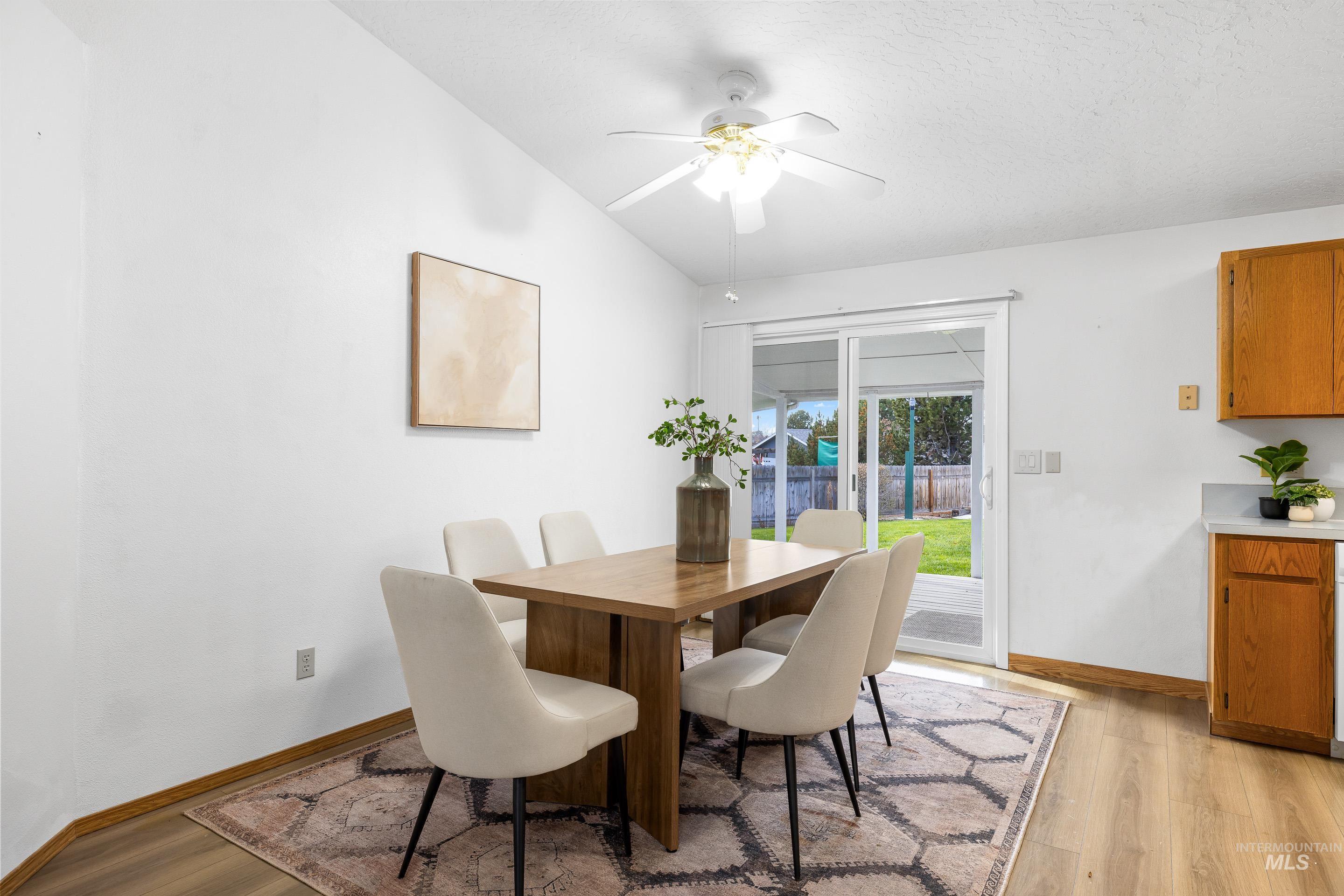 Dining room featuring light wood finished floors, a ceiling fan, and lofted ceiling