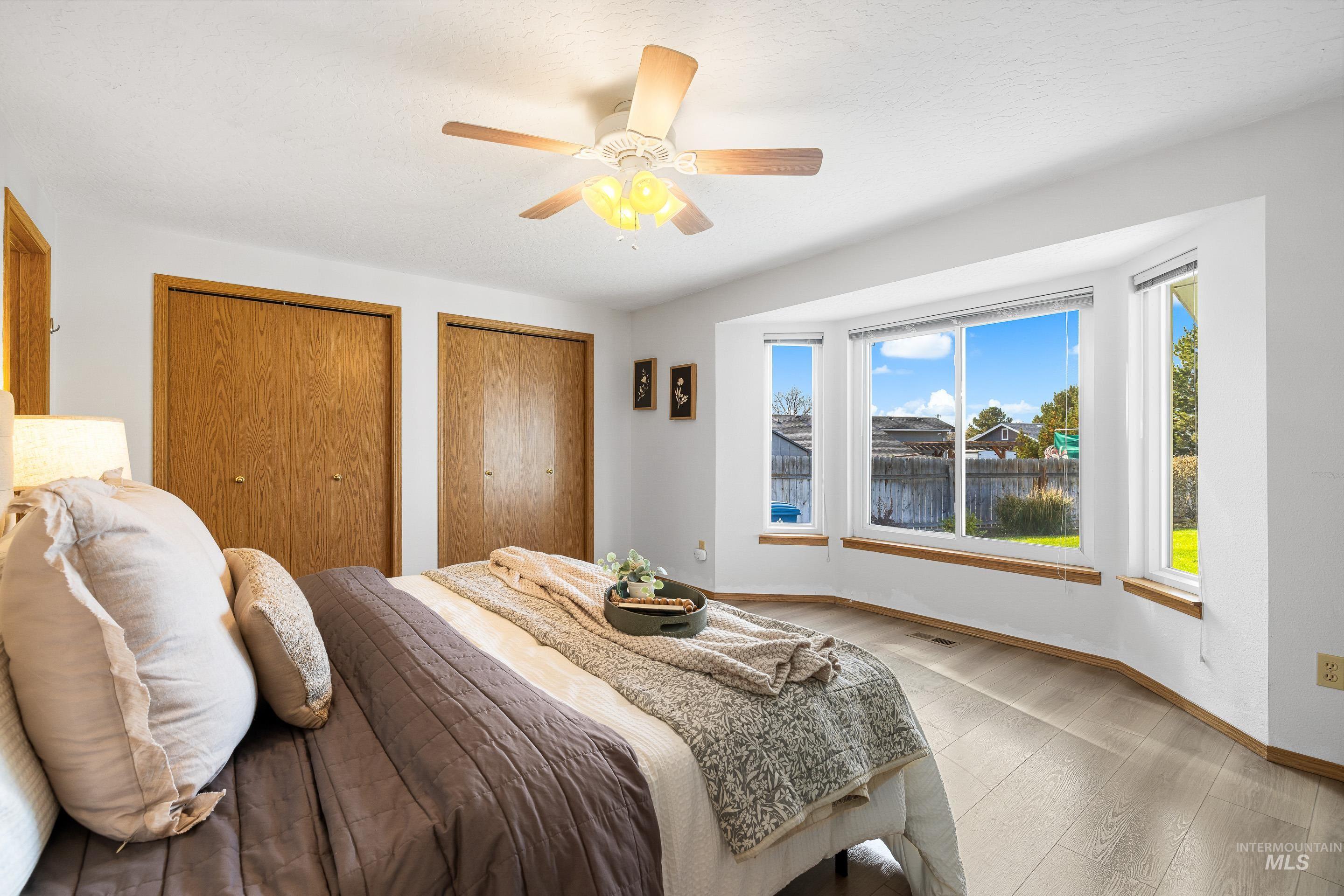 Bedroom with two closets, wood finished floors, and ceiling fan