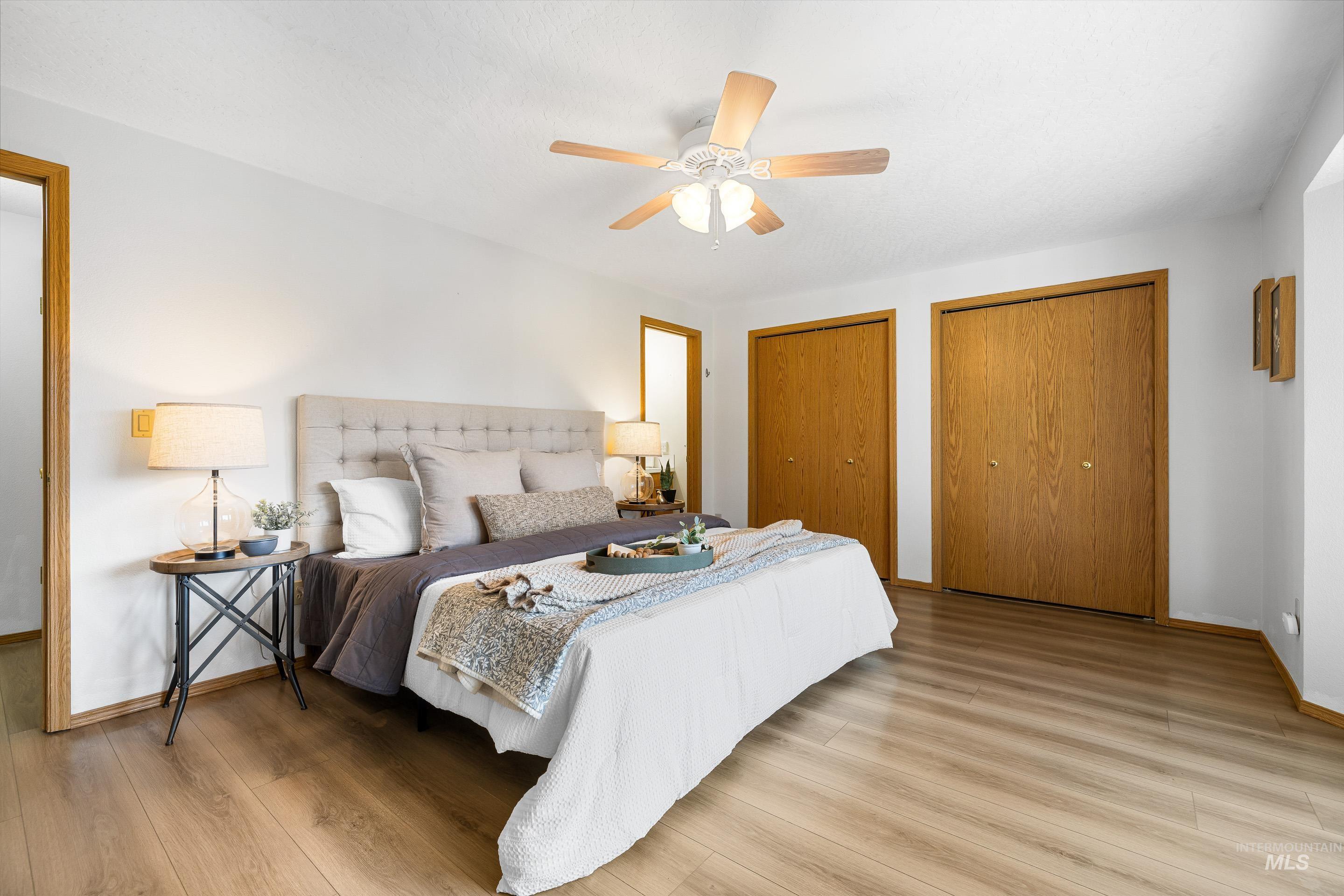 Bedroom featuring multiple closets, light wood-type flooring, and ceiling fan