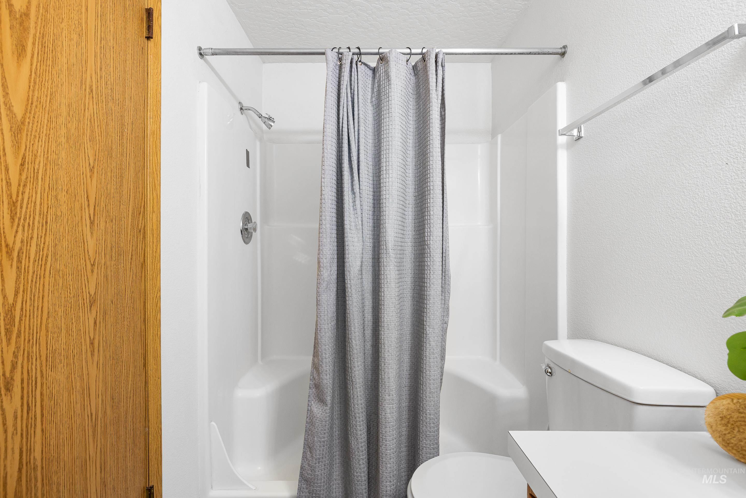 Full bath featuring a shower stall, a textured ceiling, a textured wall, and vanity