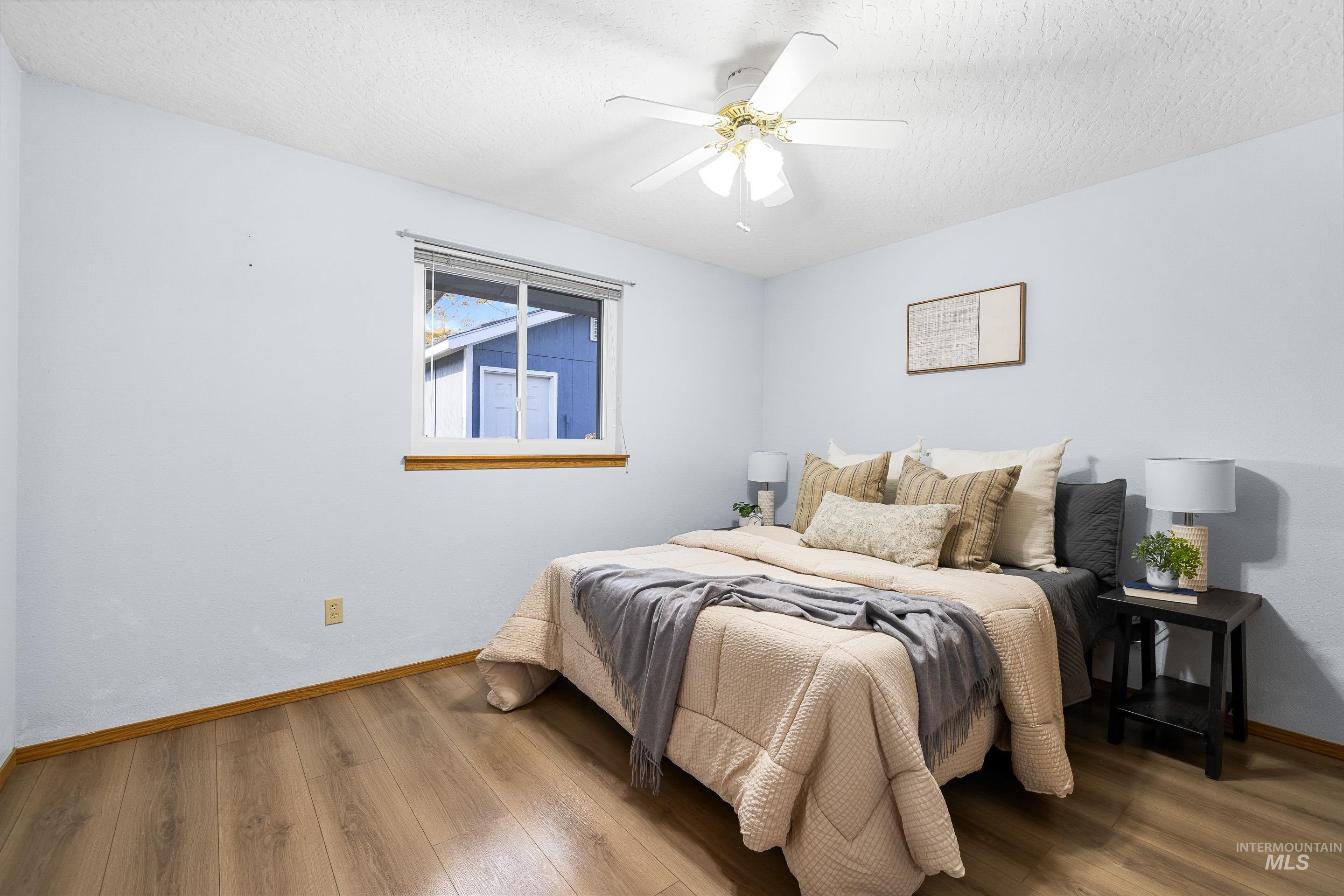 Bedroom featuring wood finished floors, a textured ceiling, and a ceiling fan