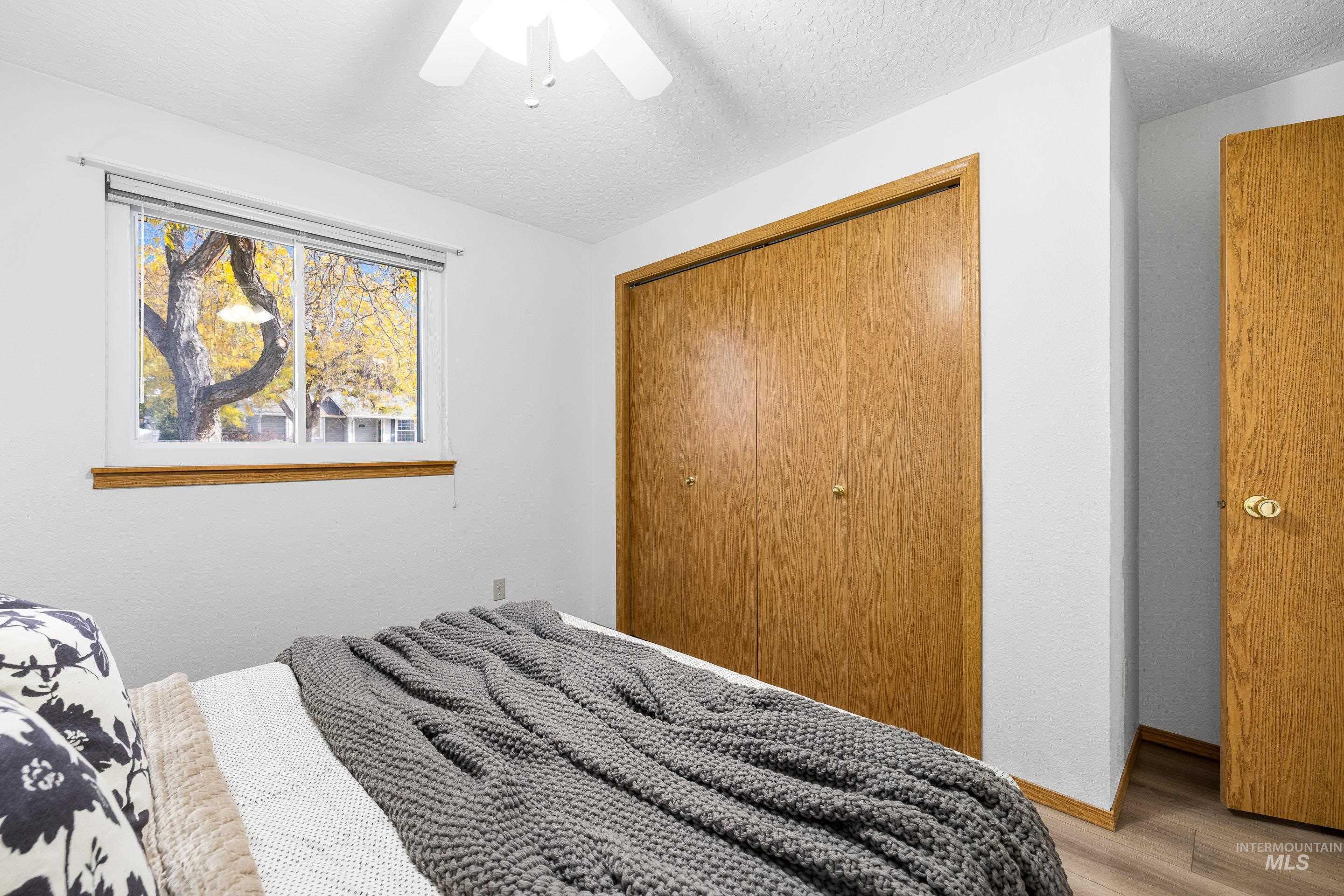 Bedroom with a closet, wood finished floors, a textured ceiling, and ceiling fan