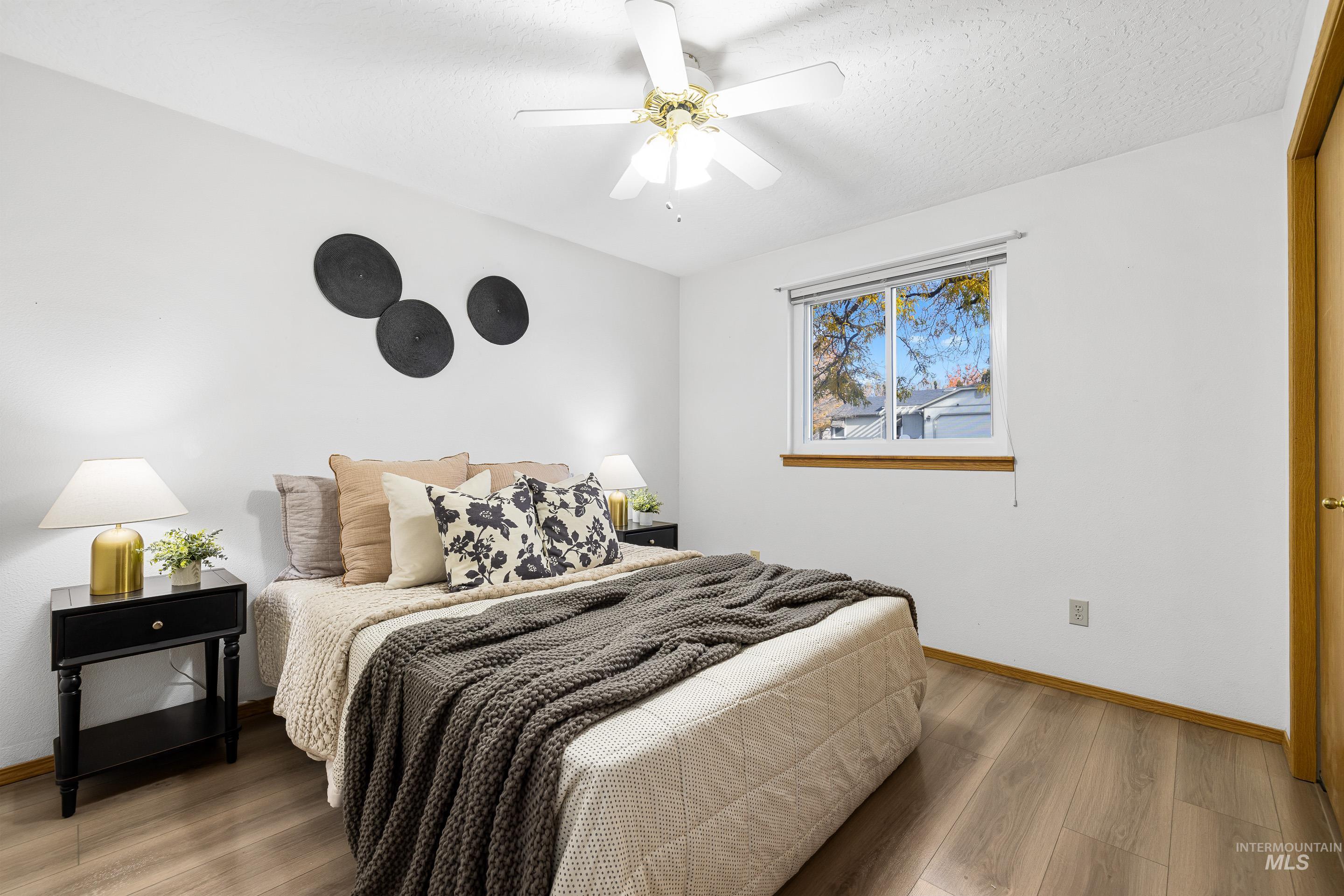 Bedroom featuring light wood-style flooring, a ceiling fan, and a textured ceiling