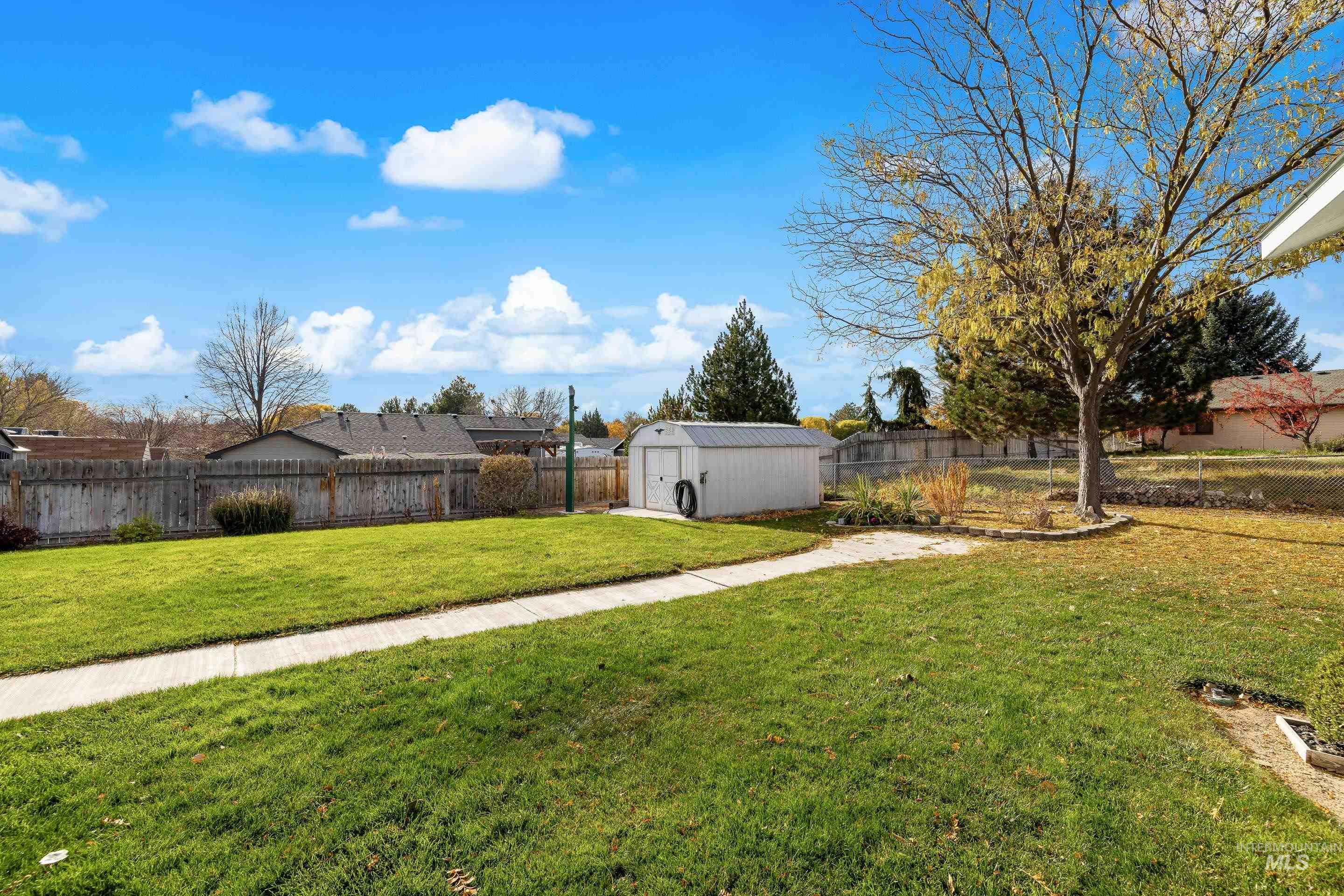 Fenced backyard featuring a shed