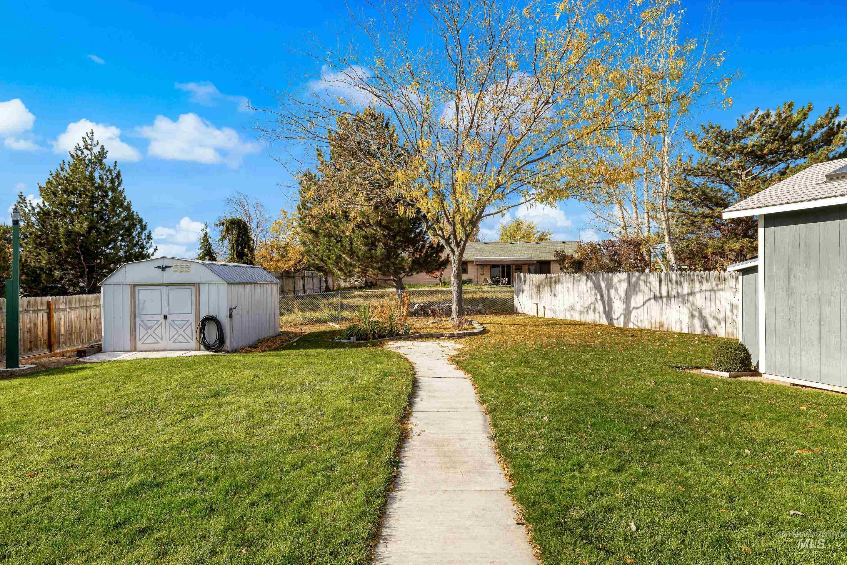 Fenced backyard featuring a storage unit
