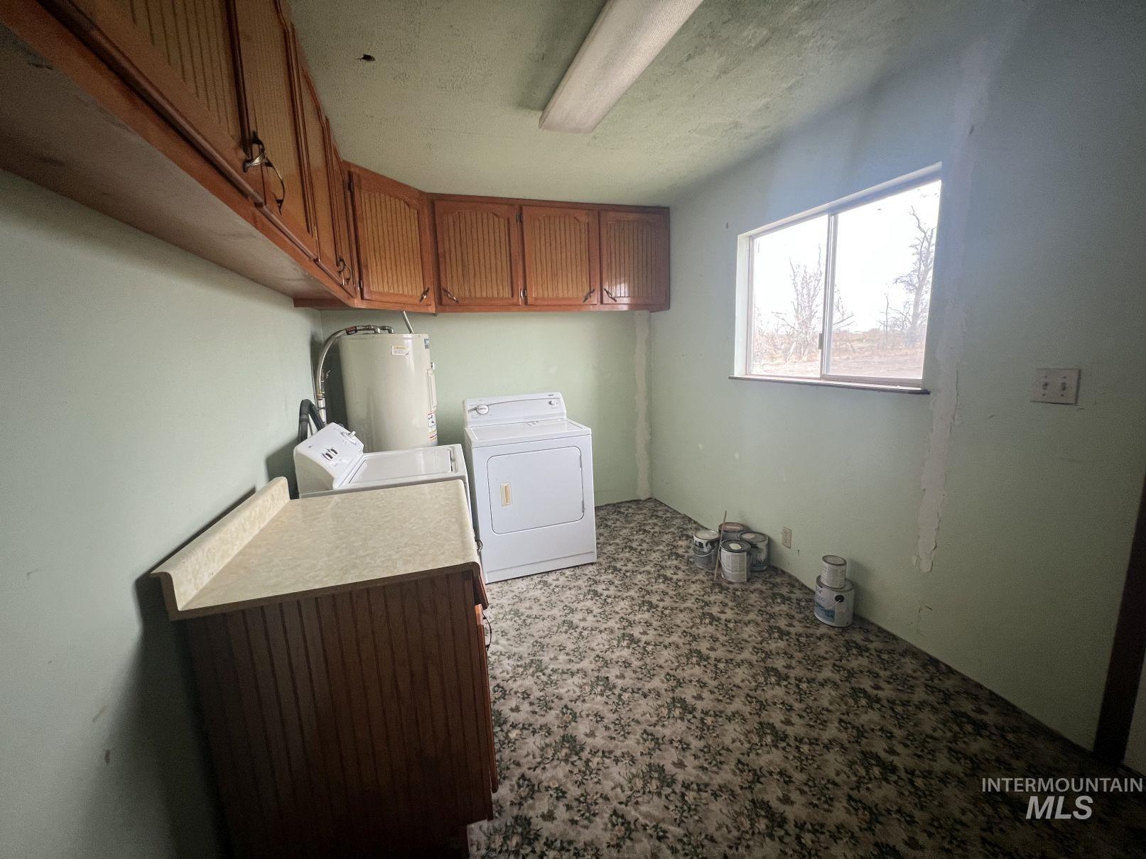 Laundry area featuring cabinet space, electric water heater, and washer and dryer