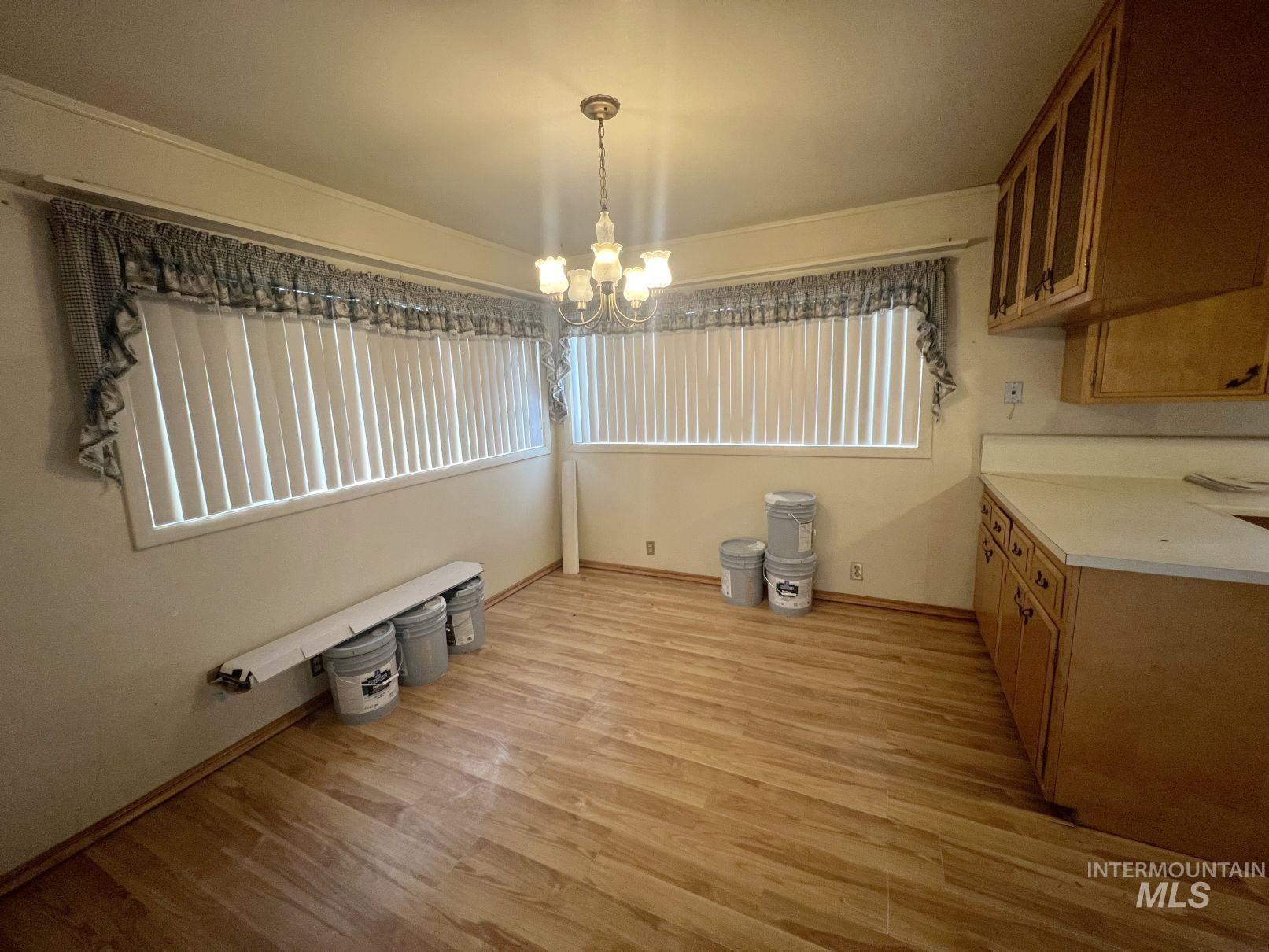 Unfurnished dining area featuring light wood finished floors, a chandelier, and healthy amount of natural light