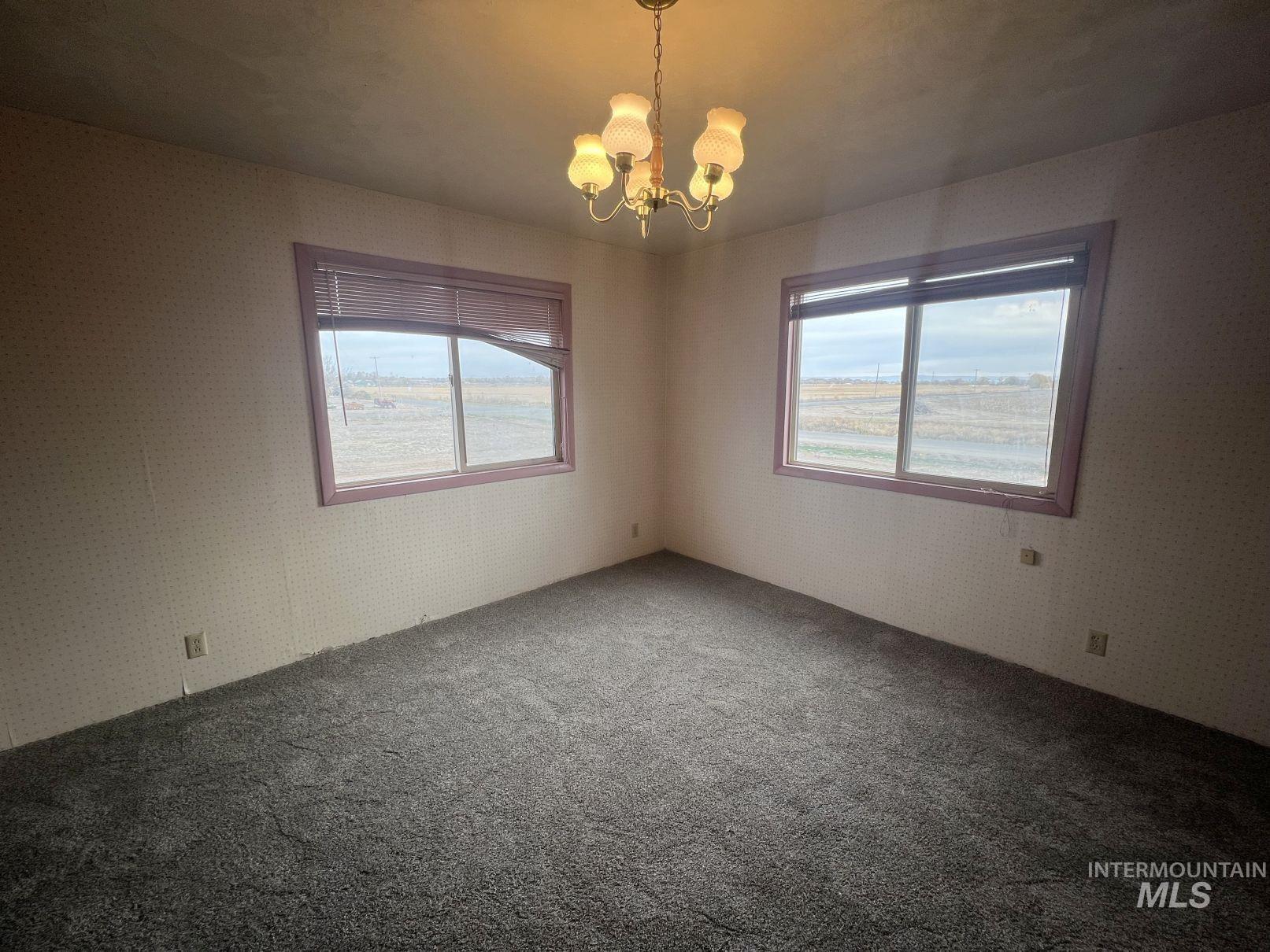 Unfurnished room featuring a chandelier and carpet flooring