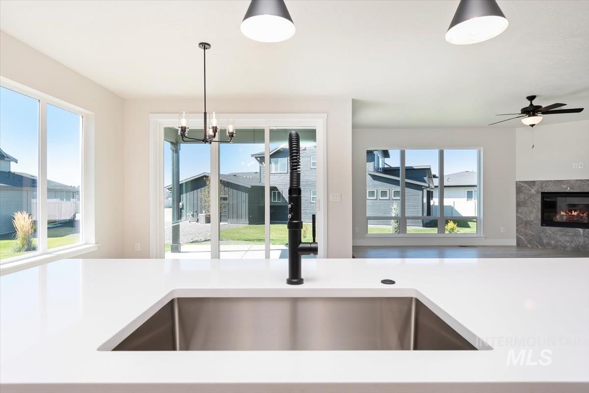 Kitchen with light stone countertops, open floor plan, a premium fireplace, pendant lighting, and a chandelier