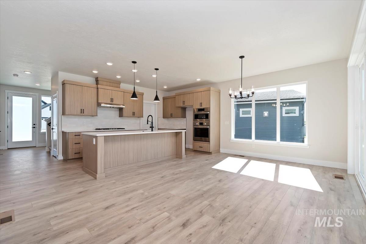Kitchen with a chandelier, decorative light fixtures, tasteful backsplash, light wood-style floors, and recessed lighting