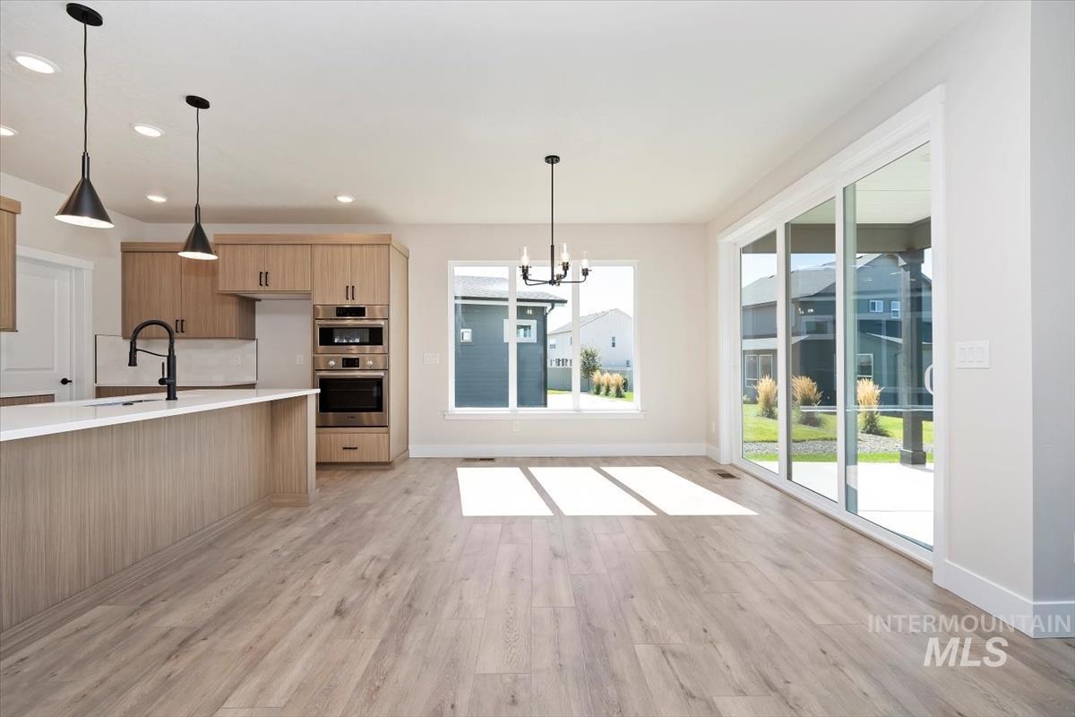 Kitchen featuring a chandelier, decorative light fixtures, light wood-style flooring, recessed lighting, and stainless steel double oven