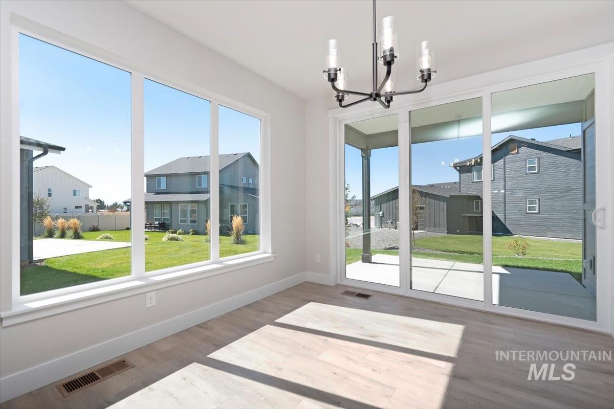 Unfurnished dining area with wood finished floors, a chandelier, a residential view, and a sunroom