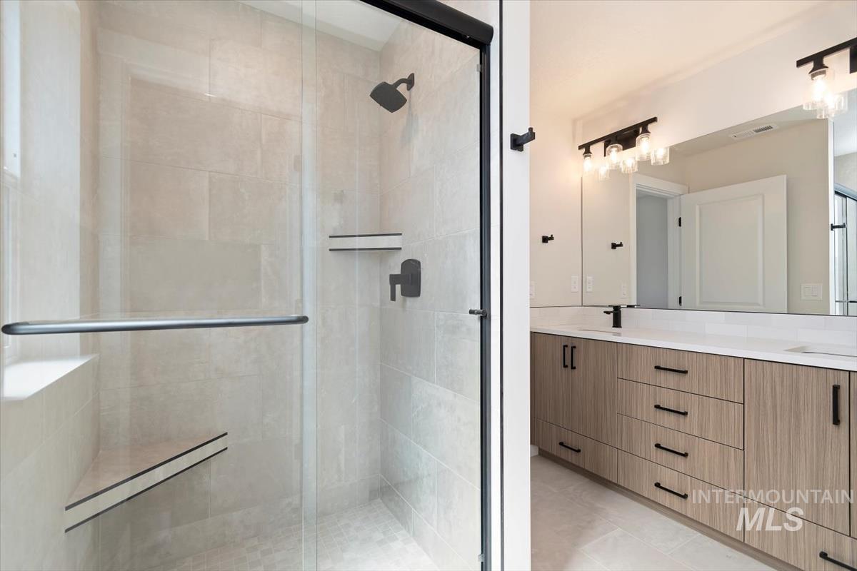Full bathroom featuring double vanity, a shower stall, and light tile patterned floors