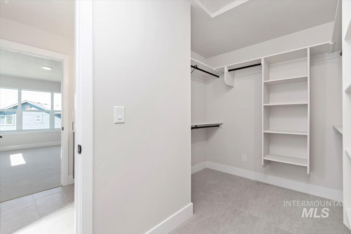 Walk in closet with light colored carpet and light tile patterned floors