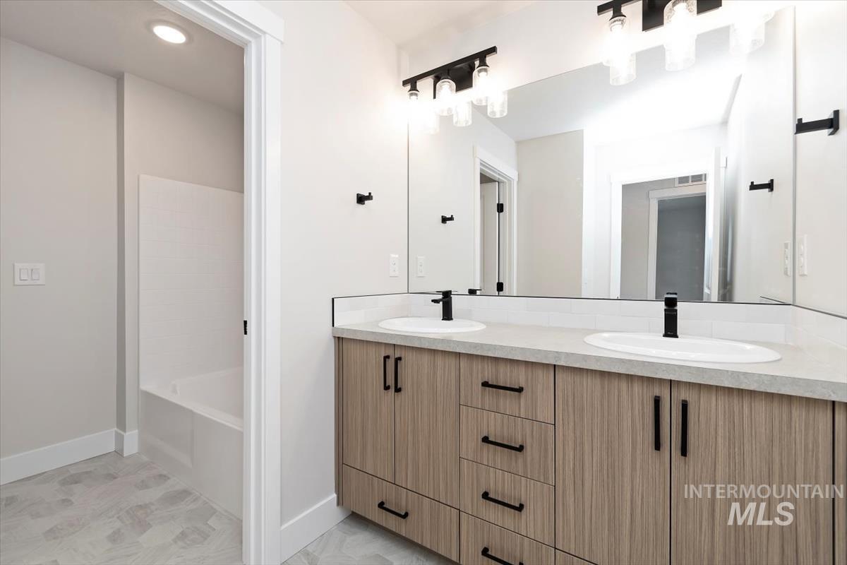Full bathroom with double vanity, a bath, and recessed lighting