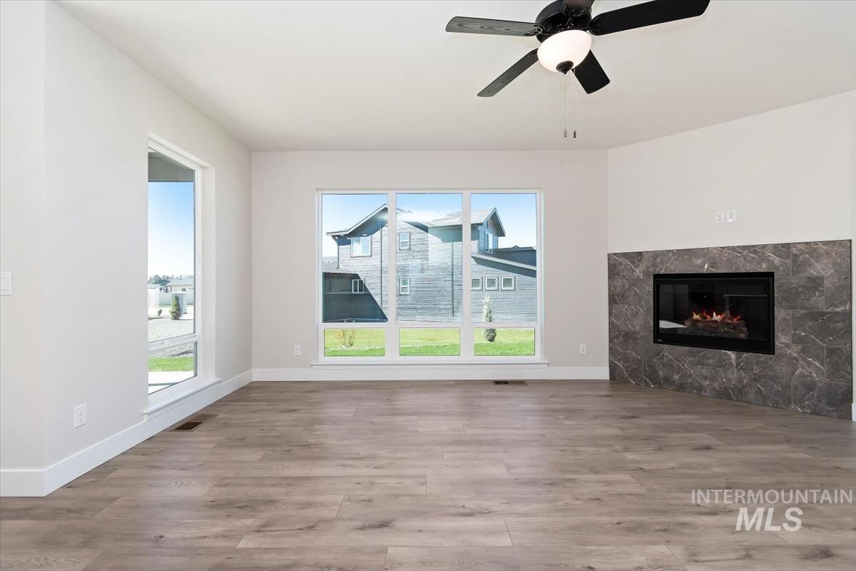 Unfurnished living room with light wood finished floors, a fireplace, and ceiling fan