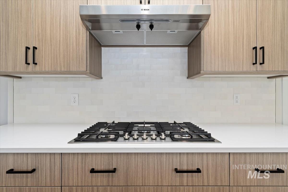 Kitchen with extractor fan, light brown cabinets, stainless steel gas cooktop, and modern cabinets