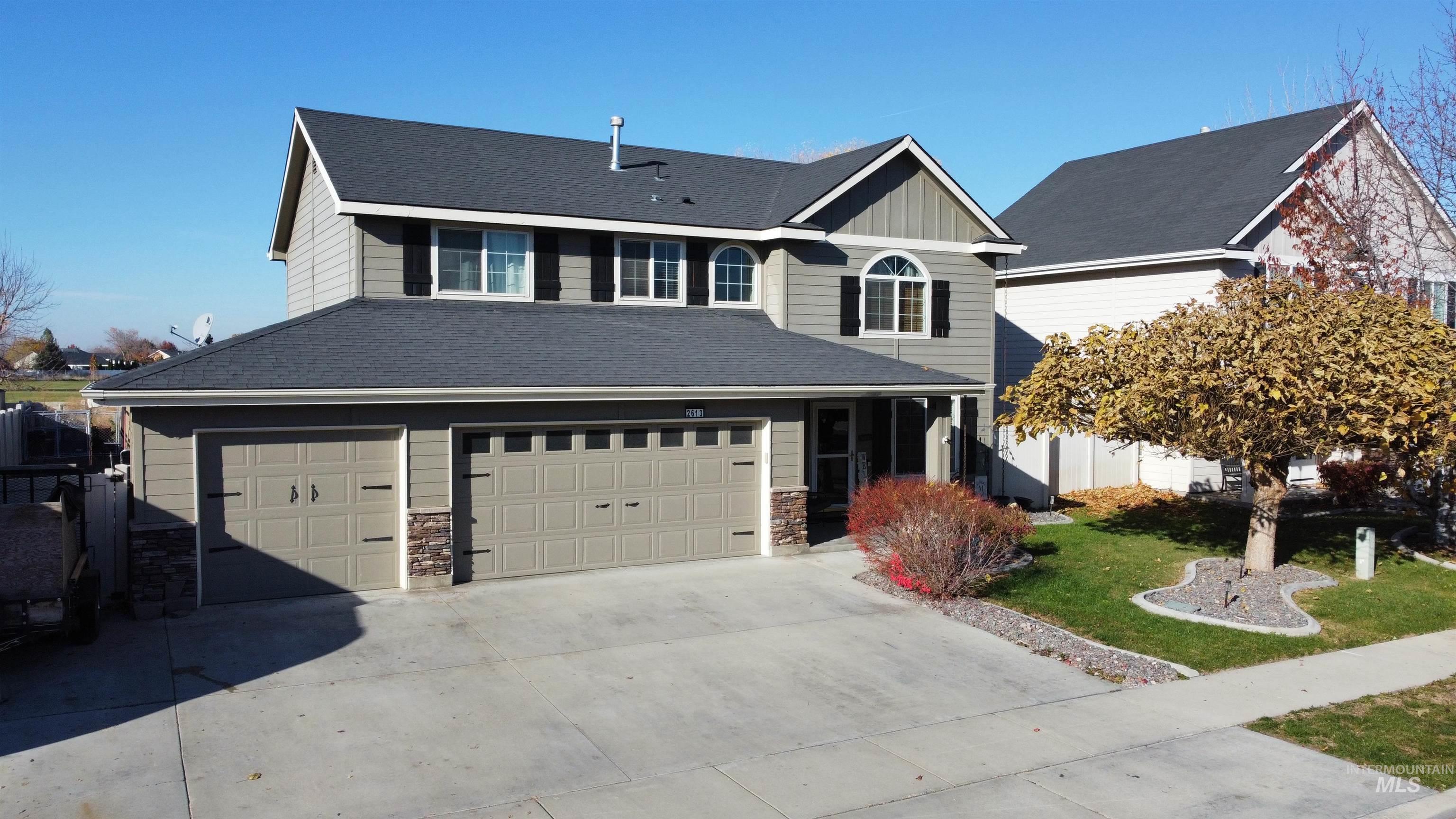 Traditional-style home featuring a front lawn, driveway, board and batten siding, a garage, and stone siding