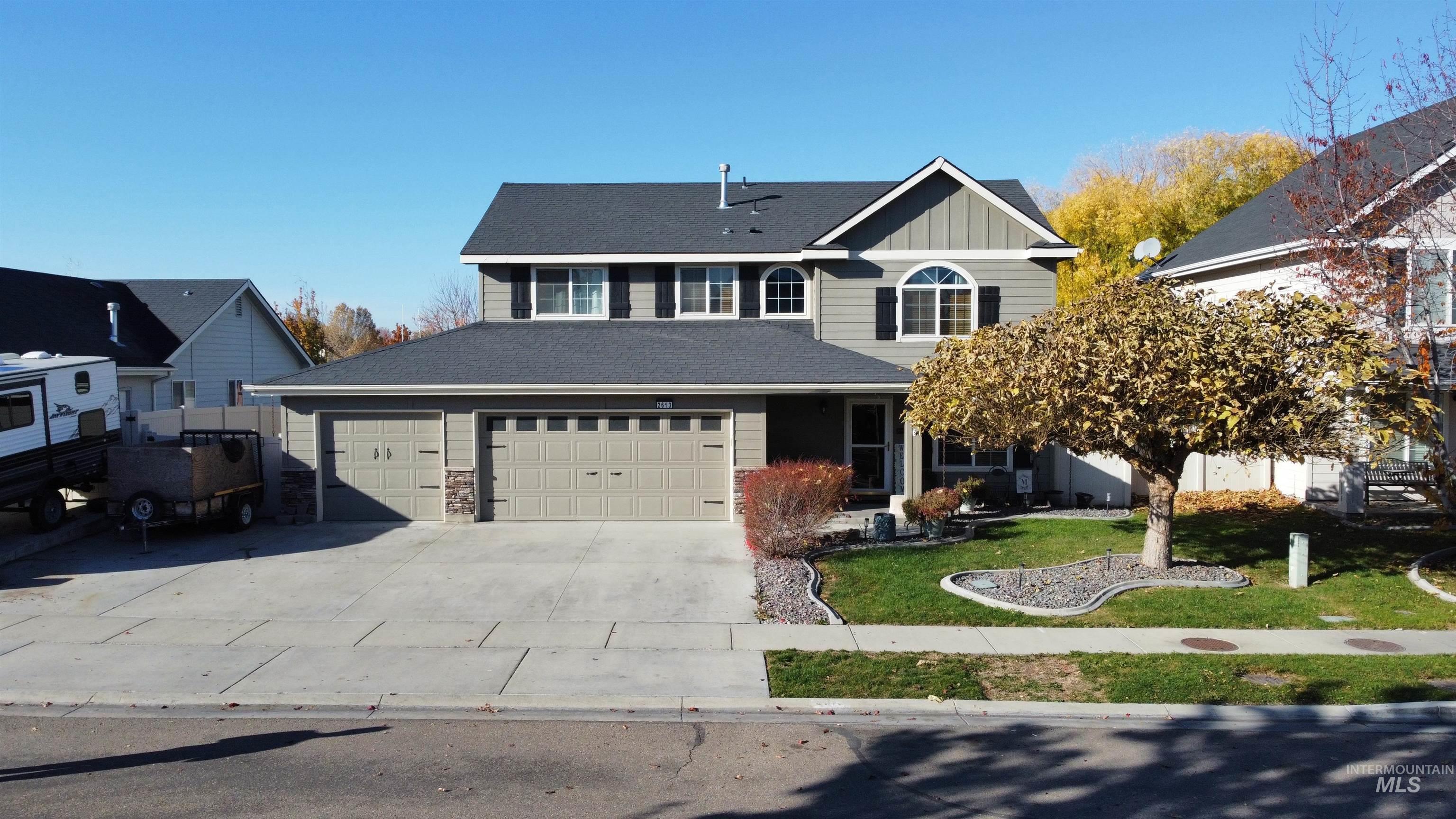 Traditional-style house with a front lawn, board and batten siding, driveway, a garage, and a porch