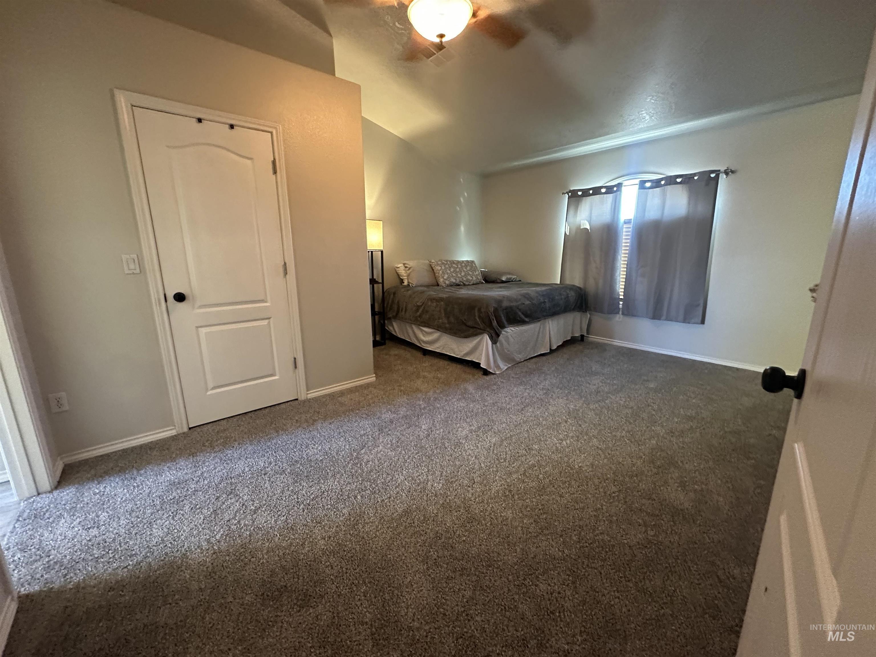 Bedroom featuring vaulted ceiling, carpet flooring, and a ceiling fan