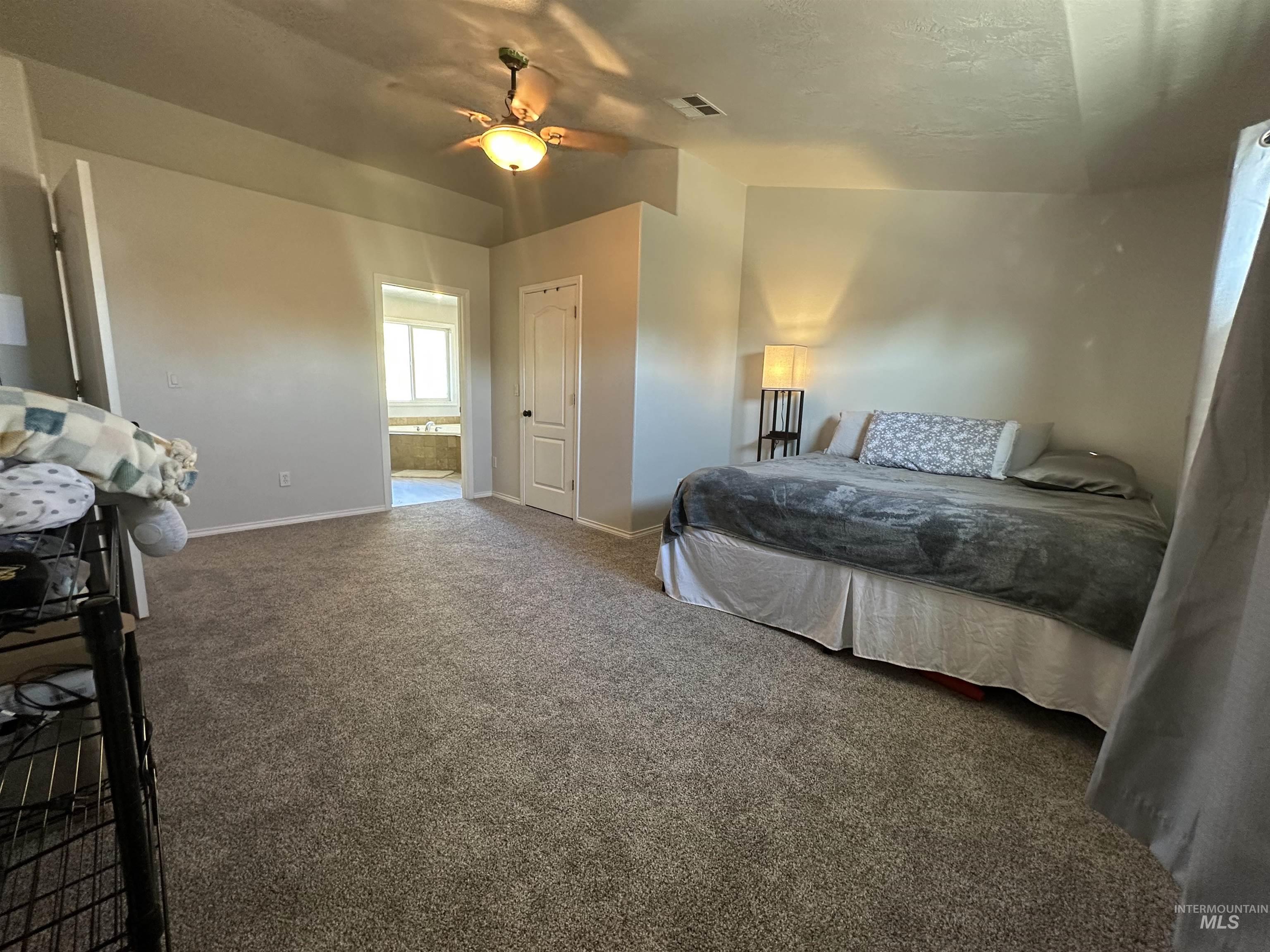 Bedroom featuring carpet, a ceiling fan, a textured ceiling, and ensuite bath
