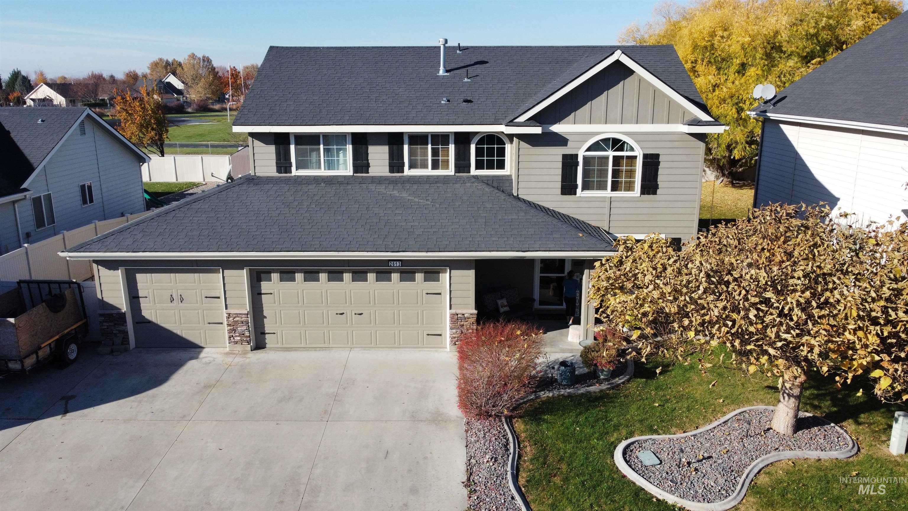 Traditional home with board and batten siding, concrete driveway, an attached garage, roof with shingles, and stone siding