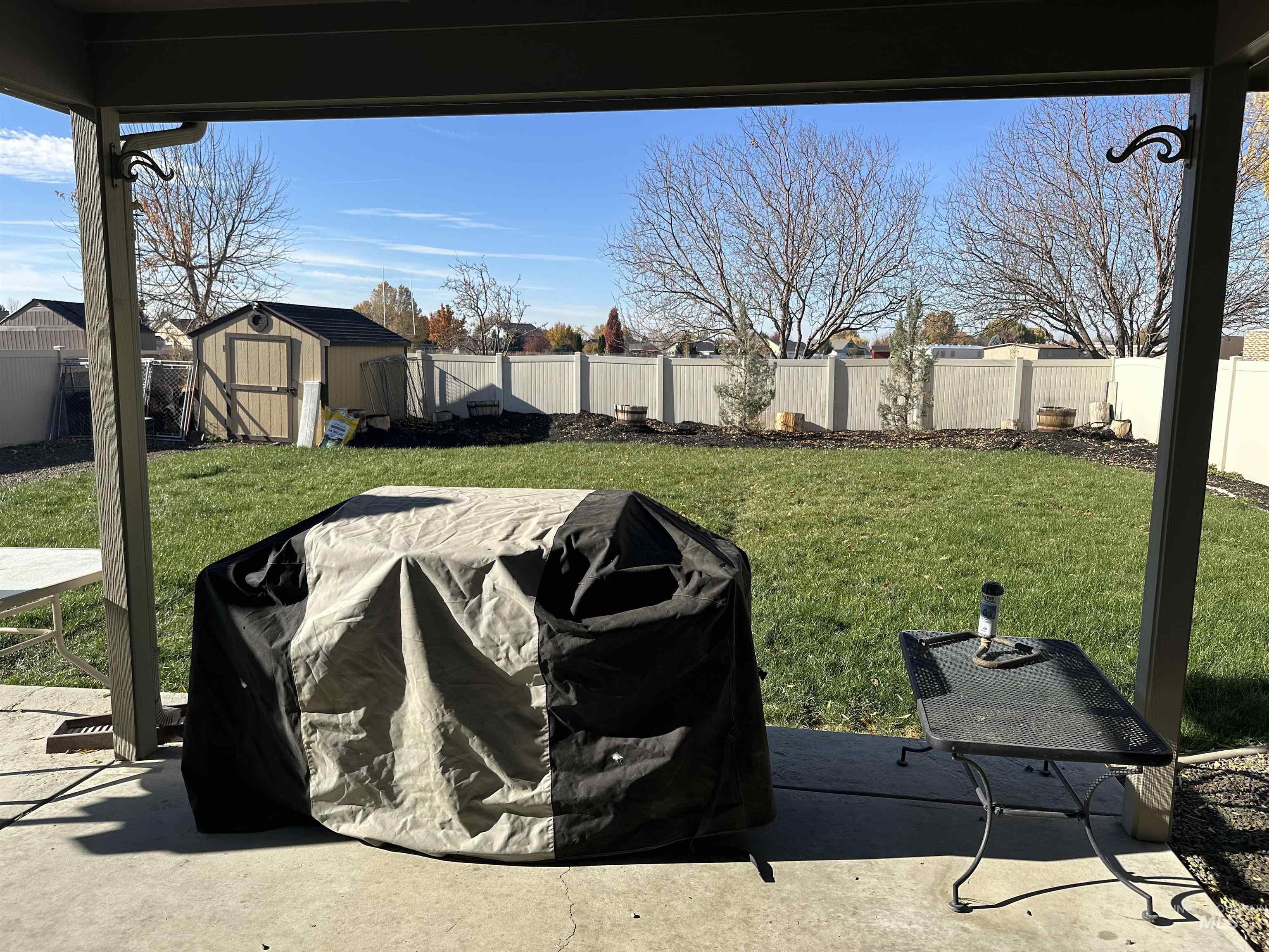 Fenced backyard with a patio and a storage unit