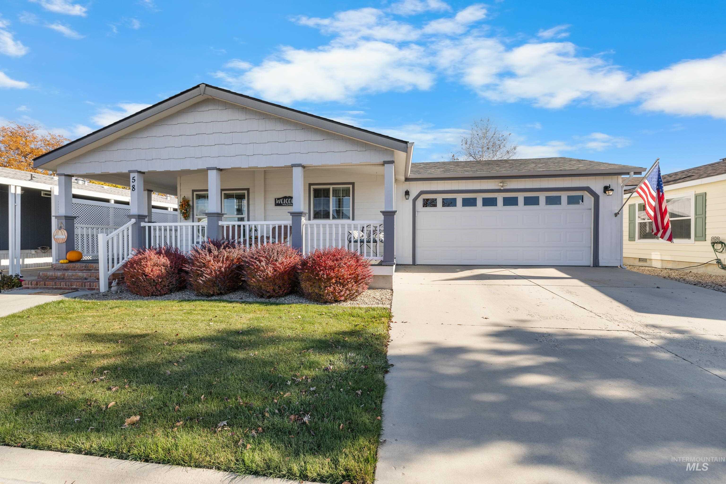 View of front of home featuring covered porch, driveway, a front lawn, and a garage