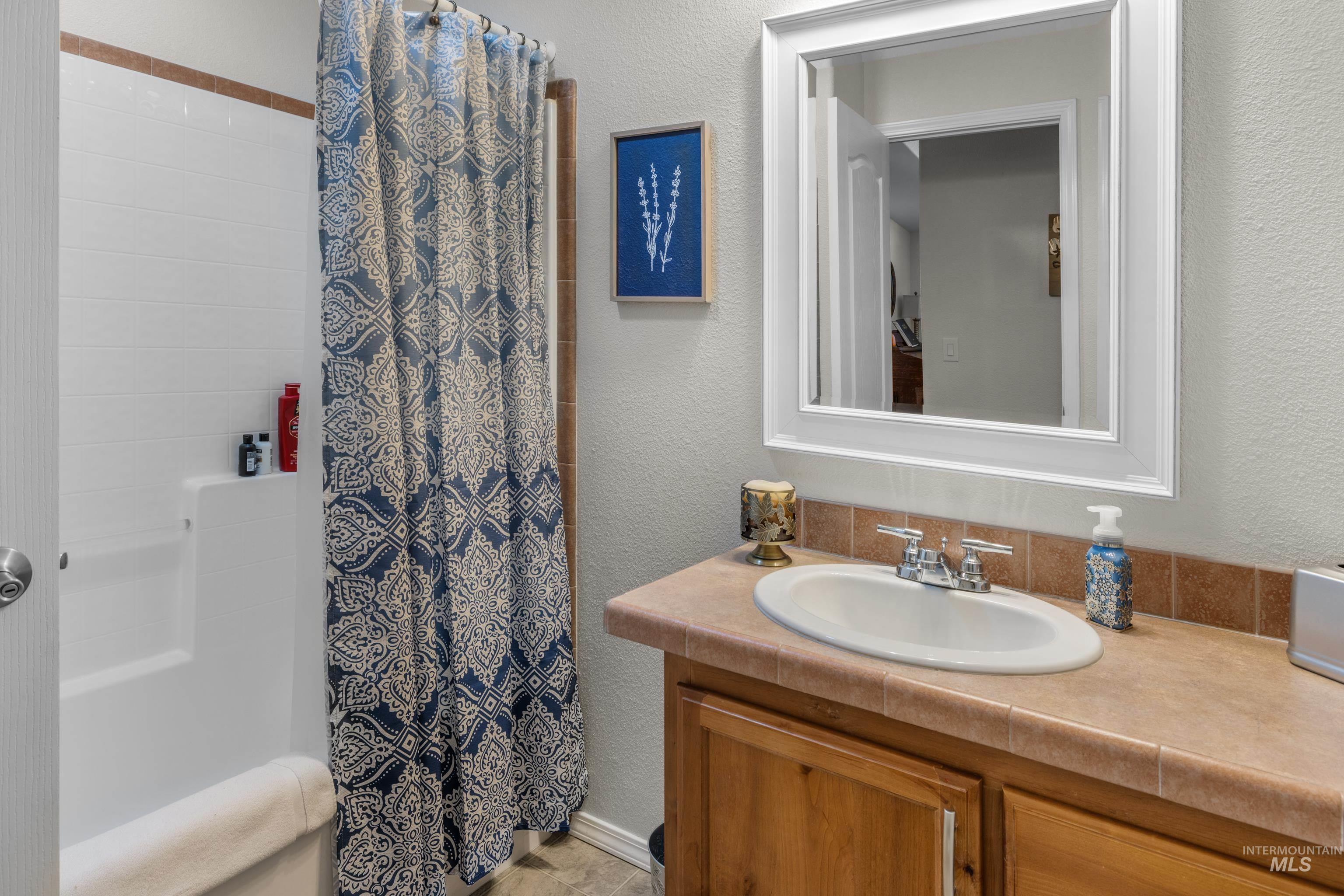 Bathroom featuring a textured wall, vanity, and a shower with shower curtain
