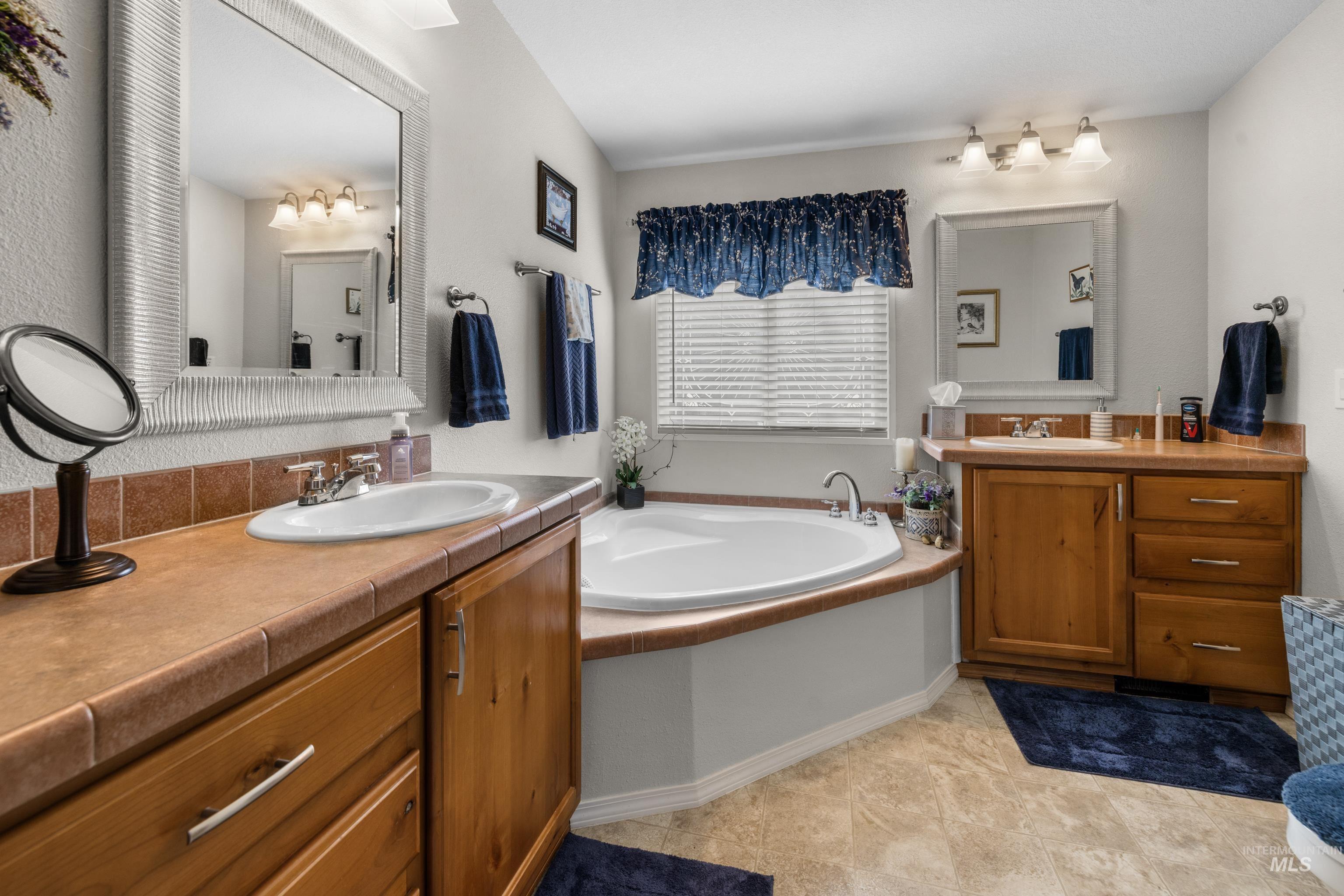 Bathroom with vanity, a bath, and light tile patterned floors