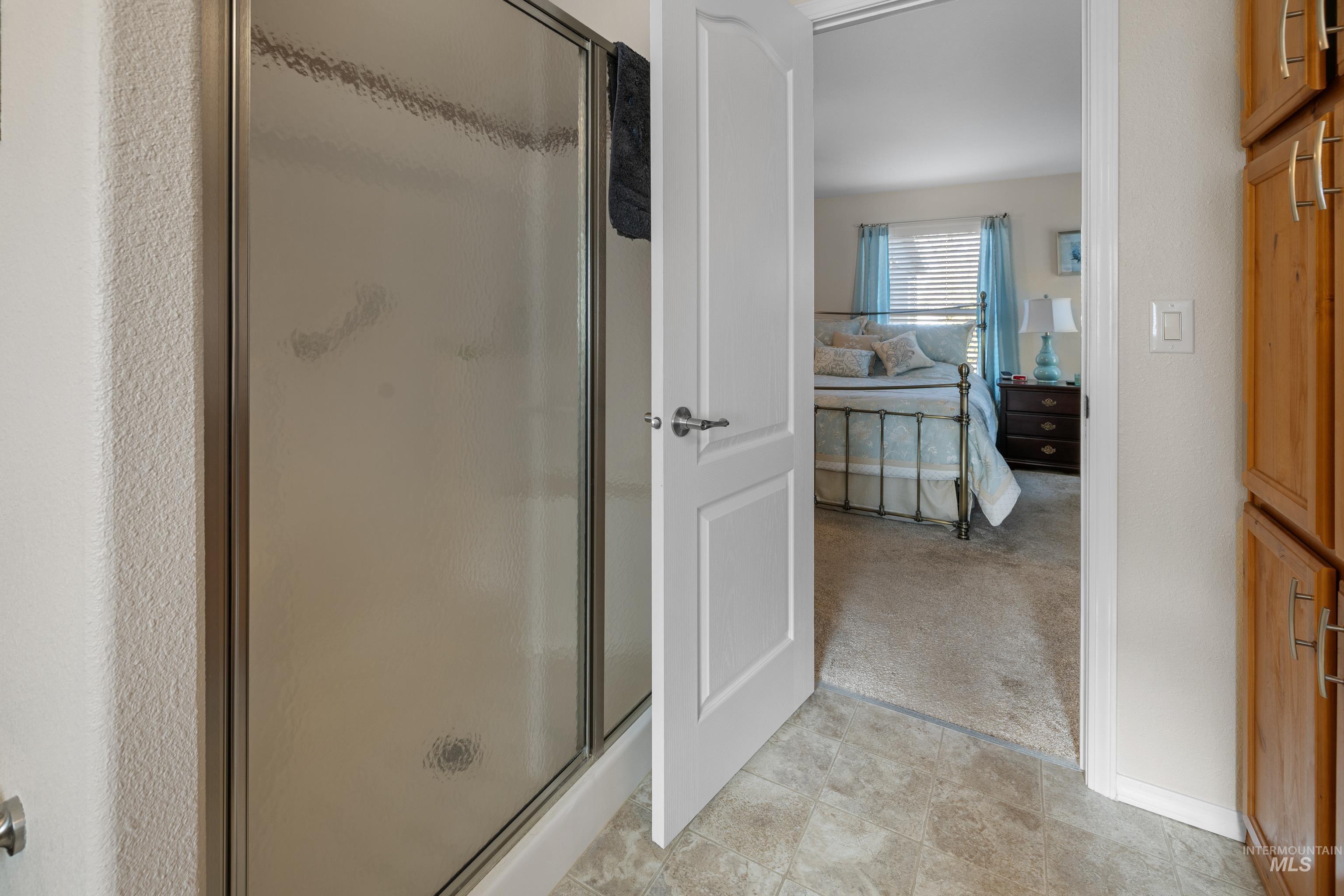 Bathroom featuring light carpet, a stall shower, and ensuite bathroom