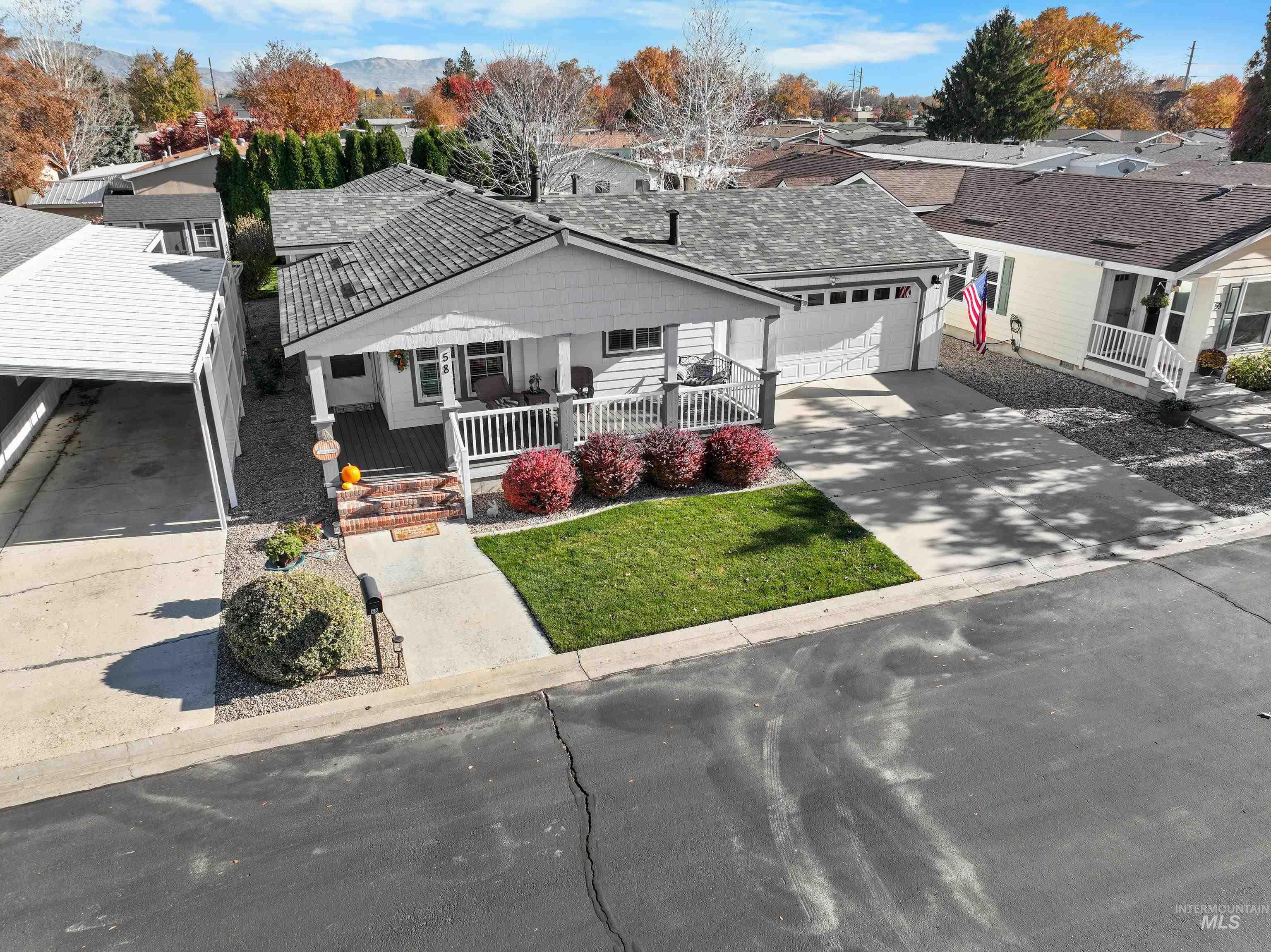 Ranch-style house featuring covered porch, concrete driveway, a residential view, and a front lawn