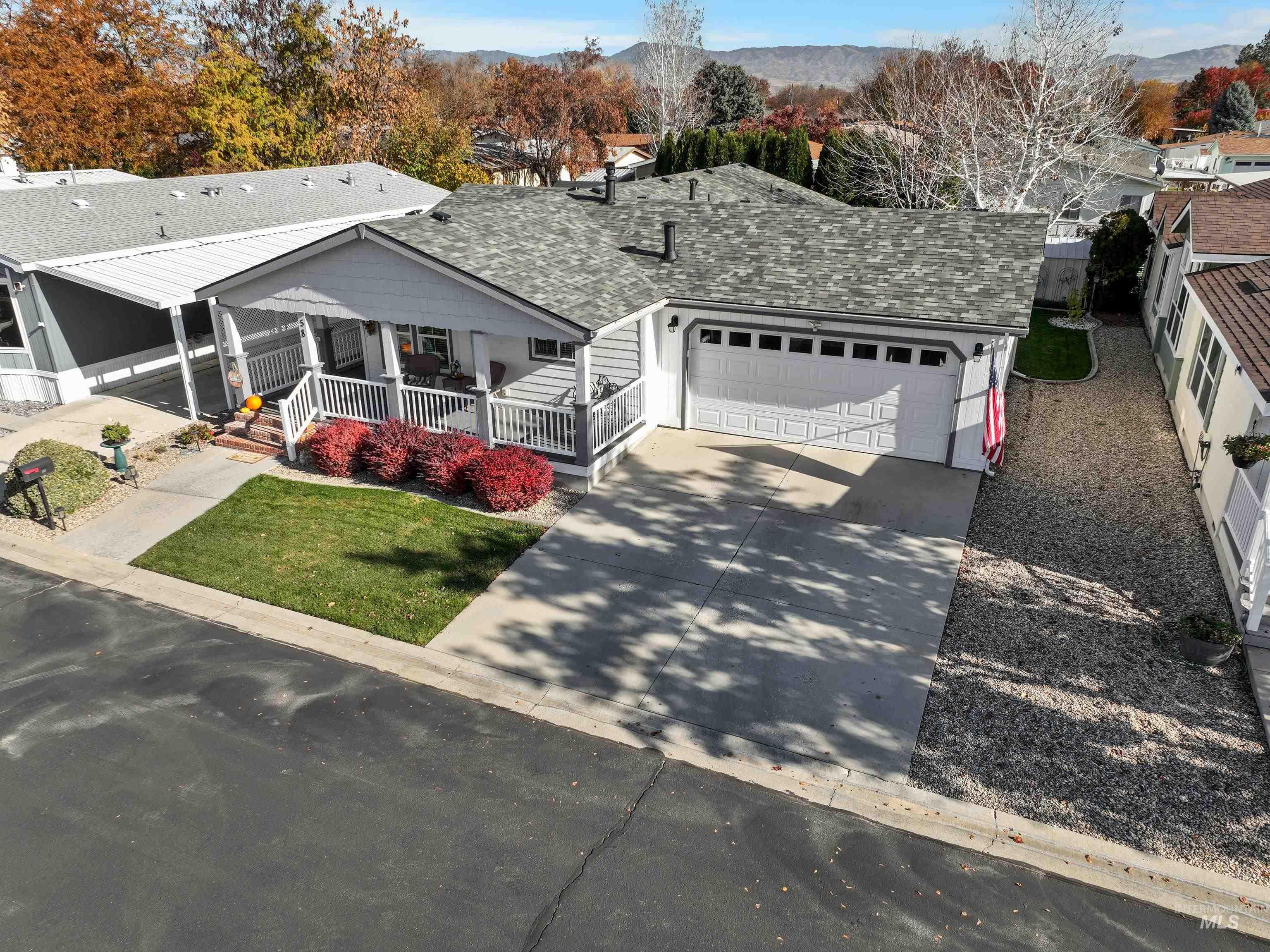 View of front facade with roof with shingles, concrete driveway, a porch, and a garage