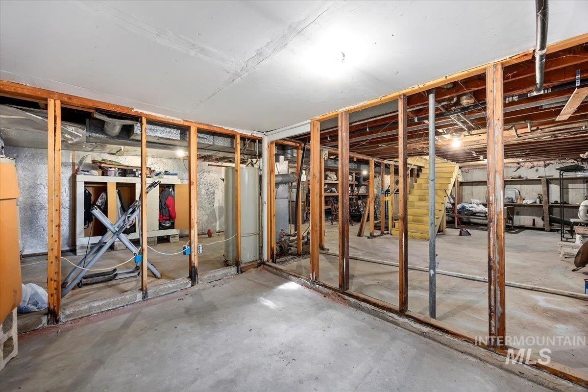 Miscellaneous room with unfinished concrete floors and water heater