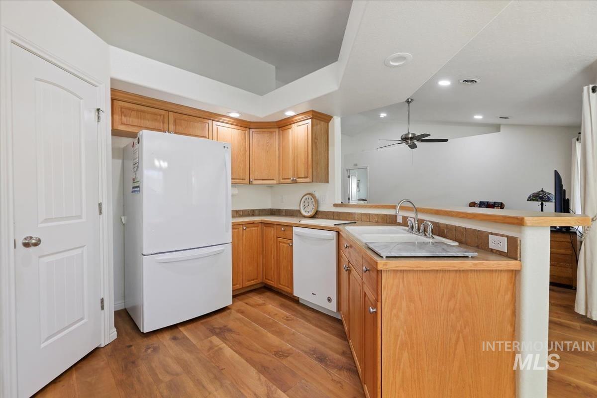Kitchen featuring white appliances, light wood-type flooring, recessed lighting, a peninsula, and light countertops