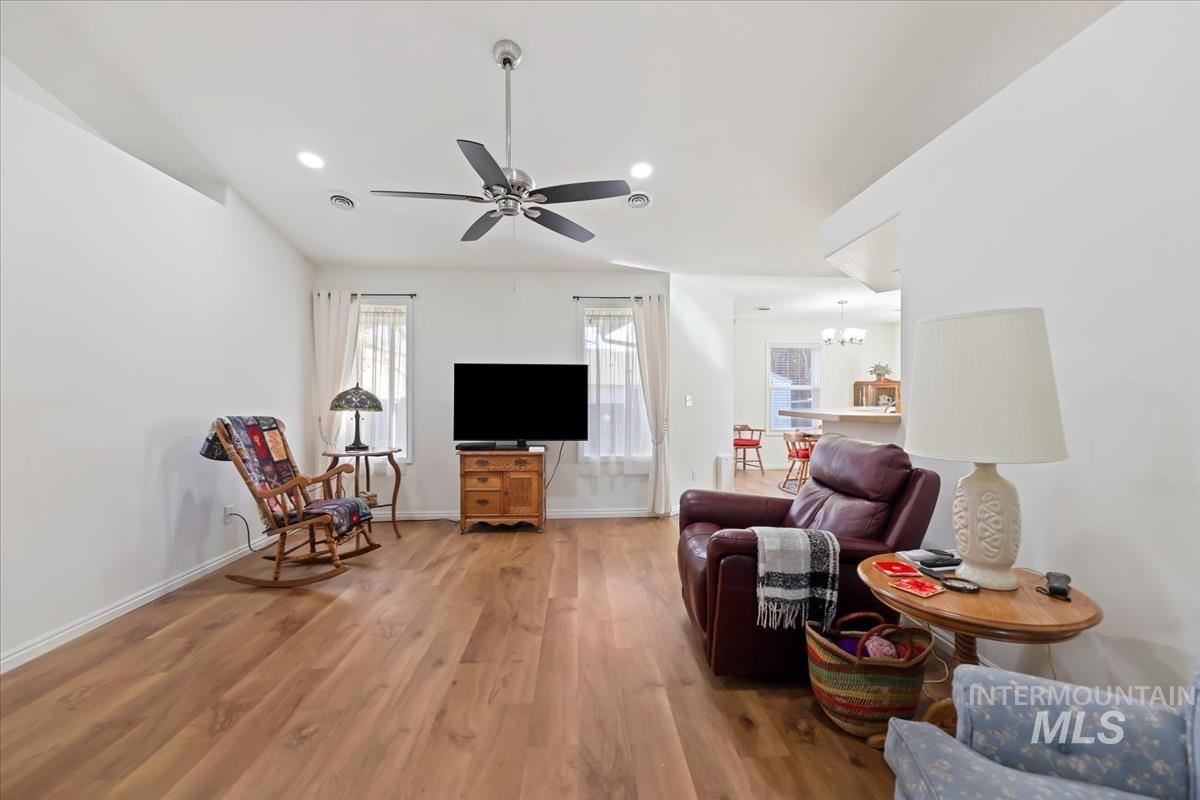 Living room featuring light wood-type flooring, a ceiling fan, recessed lighting, and a chandelier