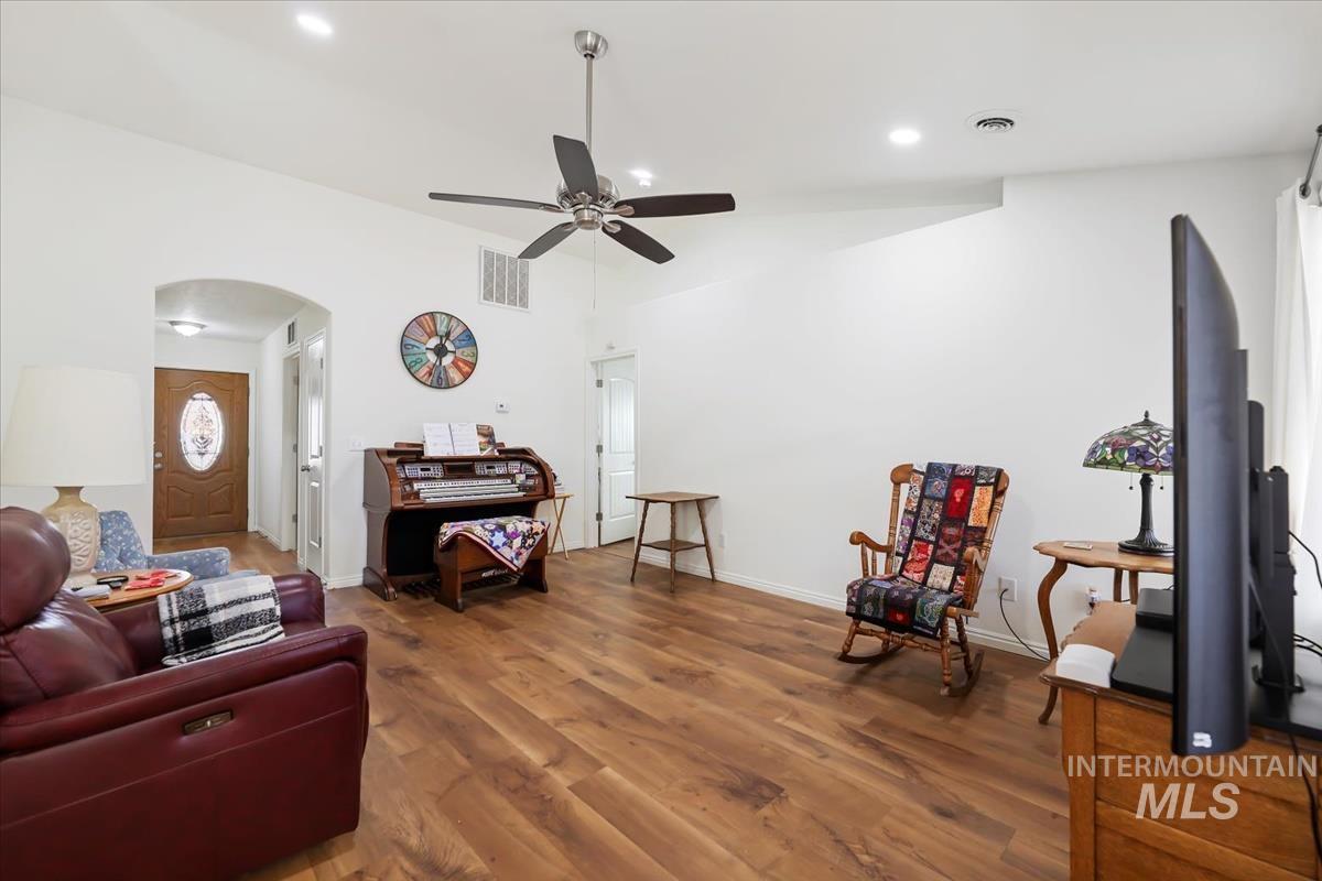 Living room featuring wood finished floors, a ceiling fan, arched walkways, and recessed lighting